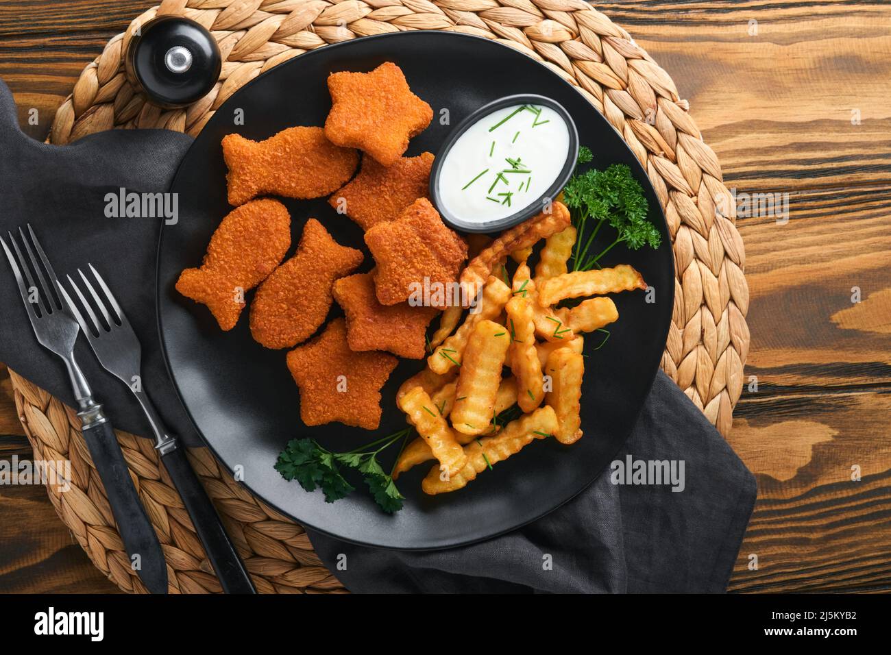 Fish and Chips, restauration rapide britannique. Bâtonnets de poisson avec frites sur plaque noire sur fond de table en bois. Plat traditionnel britannique authentique Banque D'Images