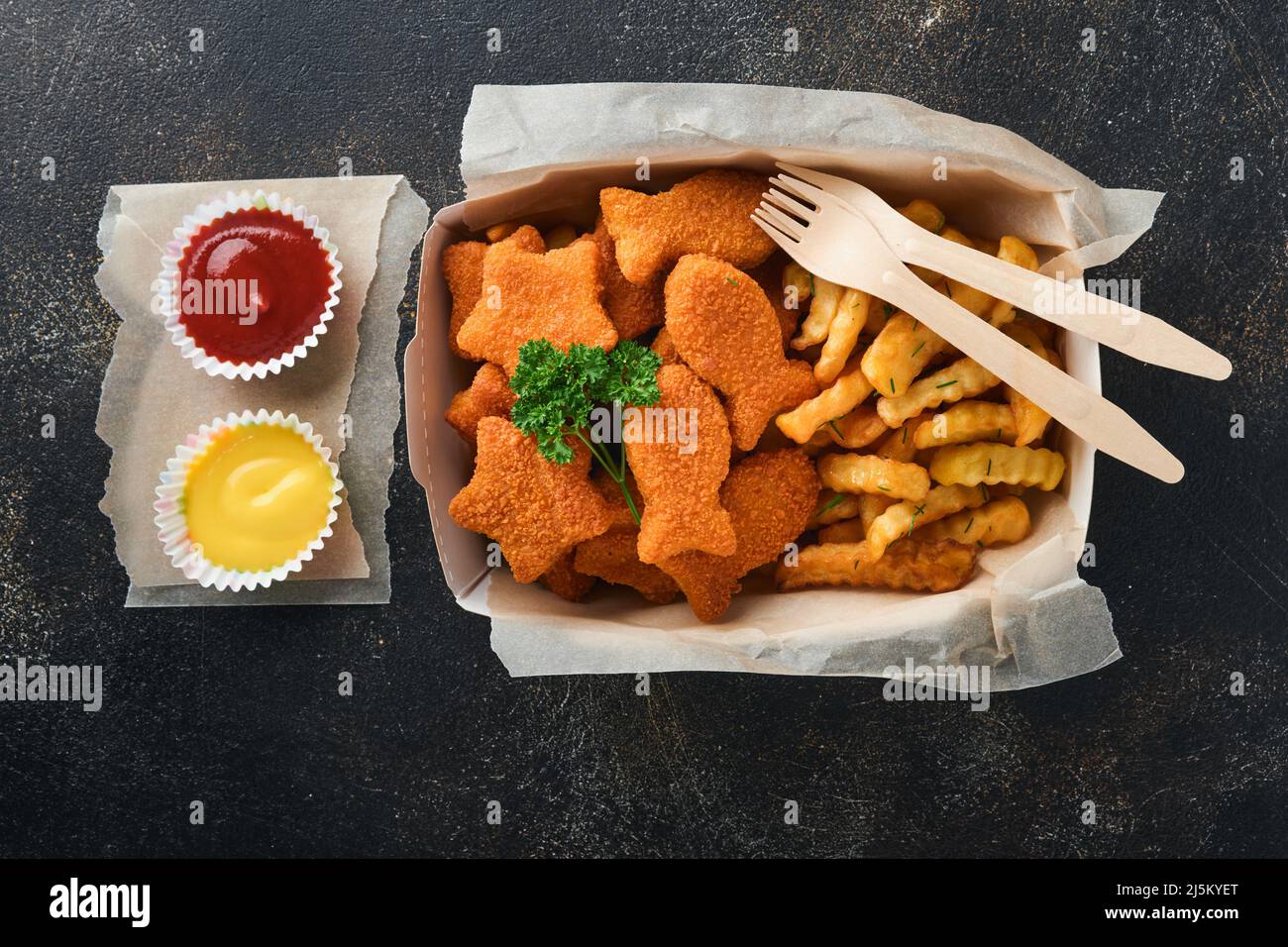 Fish and Chips, restauration rapide britannique. Bâtonnets de poisson avec frites sur une plaque de papier à emporter sur fond de béton ancien sombre. Traditionnel anglais authe Banque D'Images