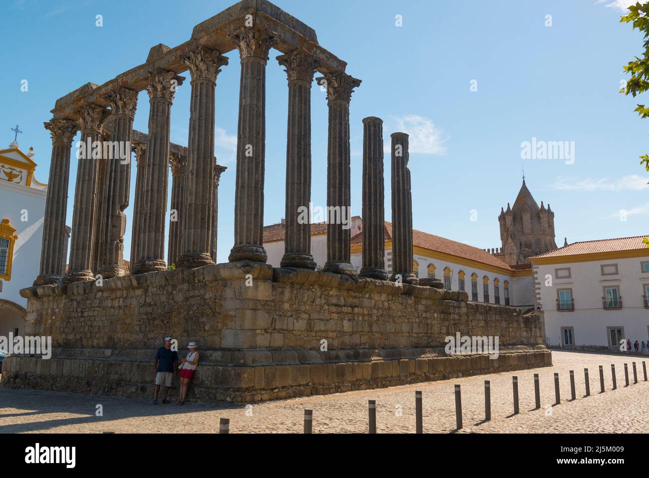 Un couple de touristes se penchant contre les vestiges du temple romain d'Evora, Portugal. La tour de la cathédrale en arrière-plan Banque D'Images