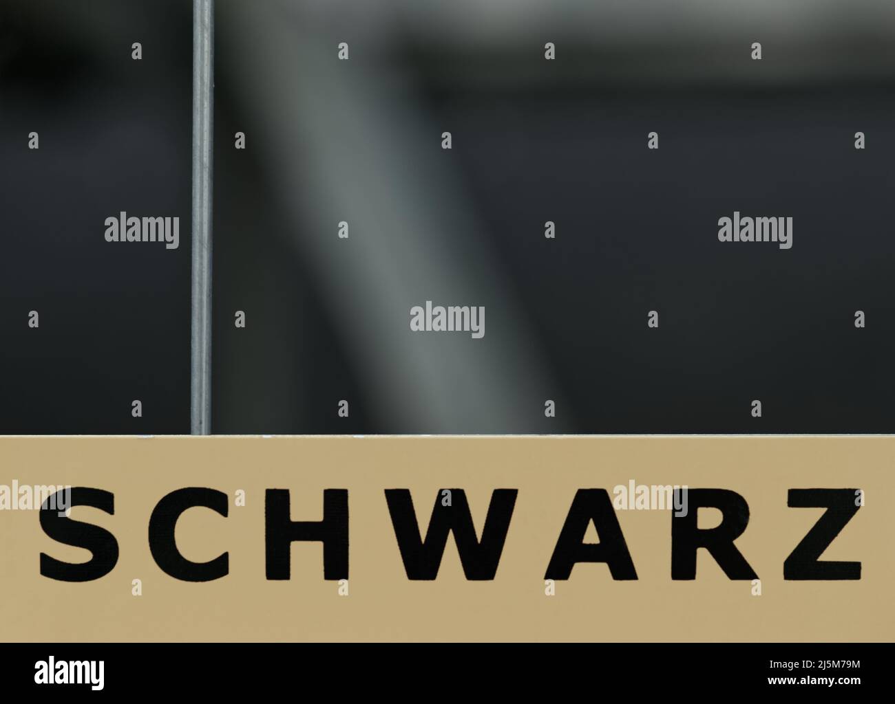 Plaque portant le libellé « CHWARZ » (allemand pour « NOIR ») sur un sol beige clair au bas de l'image et espace libre en haut avec un arrière-plan sombre Banque D'Images