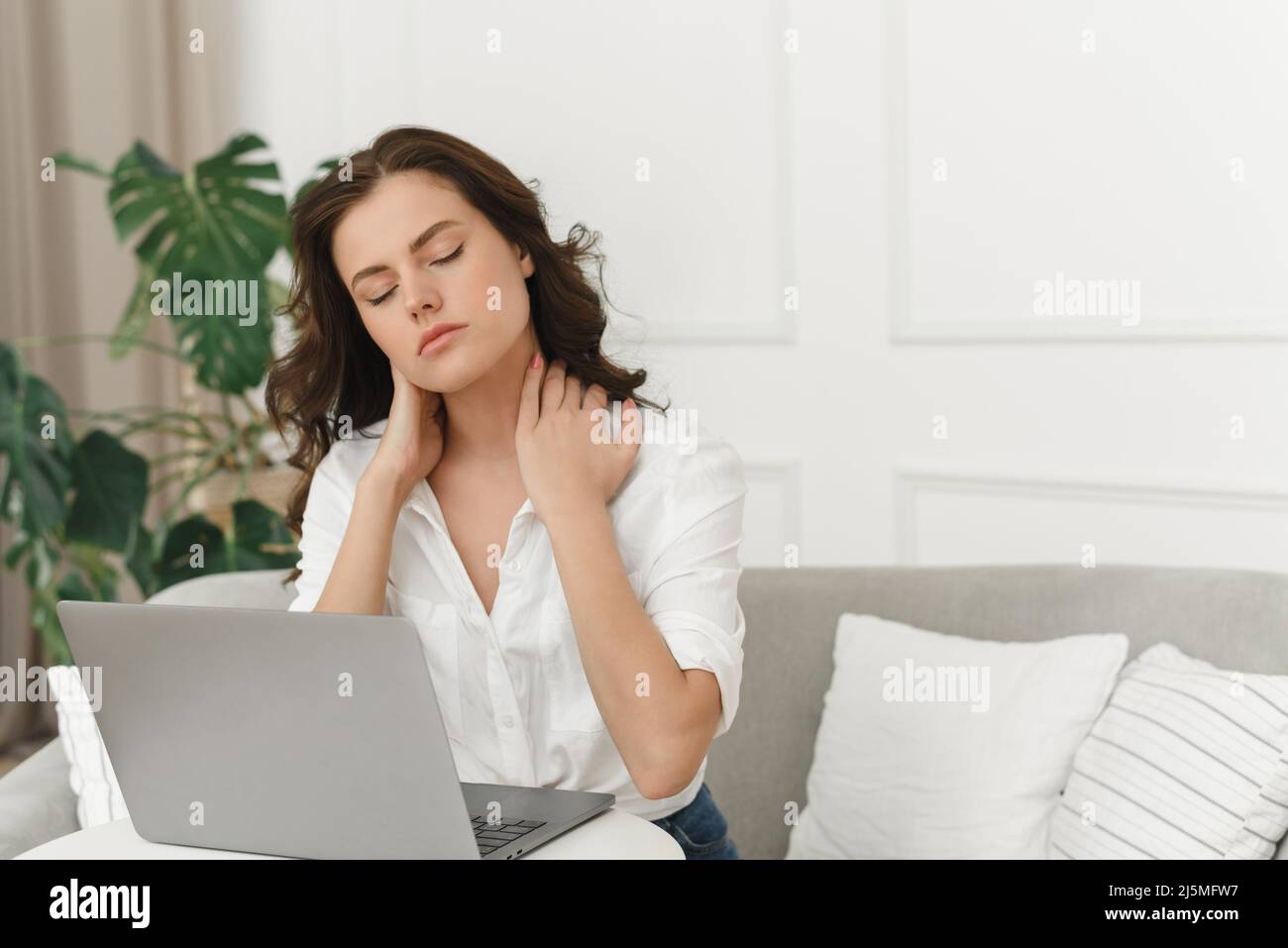 Jeune femme indépendante travaillant à domicile et éprouvant des douleurs au cou. Beaucoup de travail à la maison. Banque D'Images