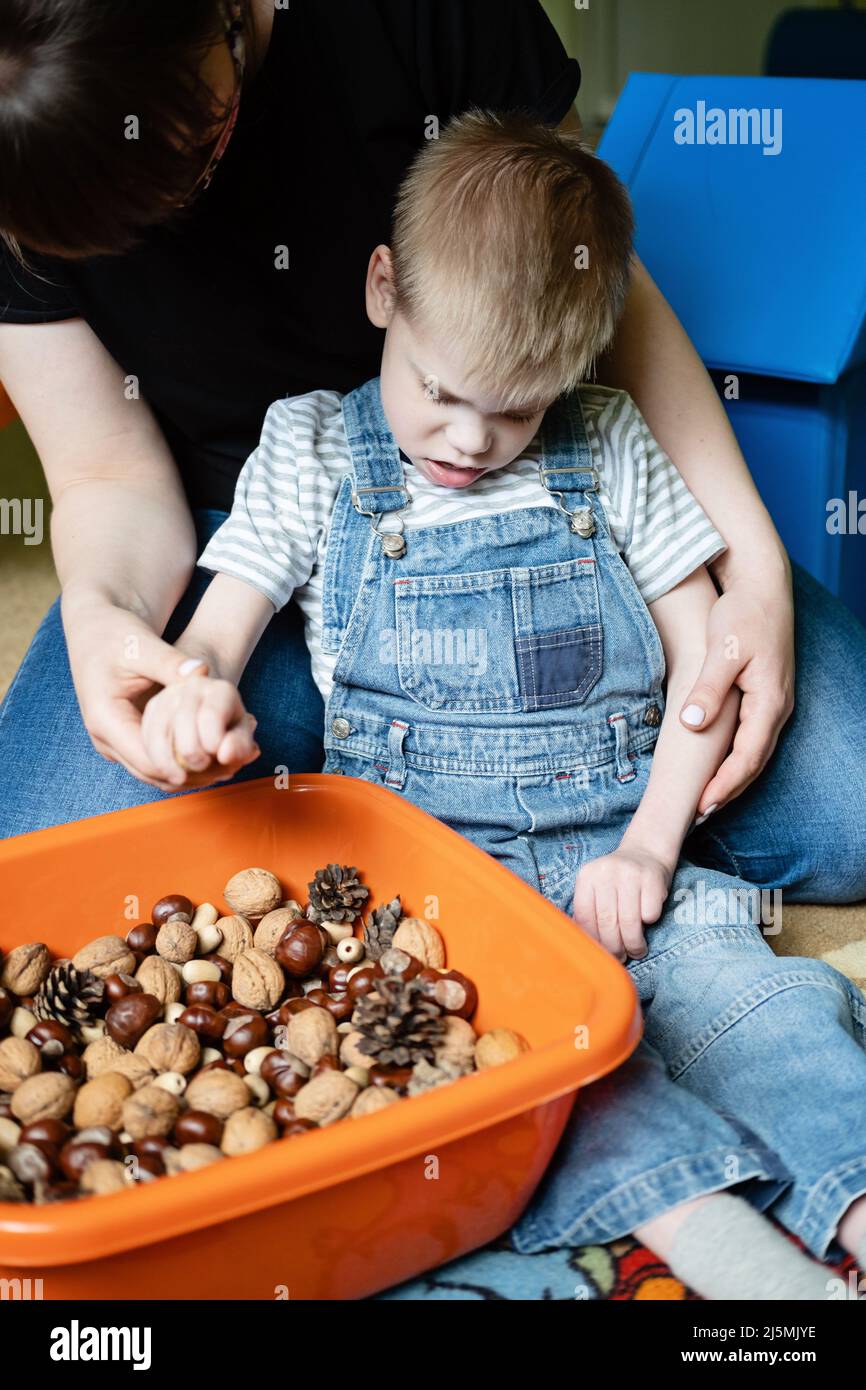 Jeu sensoriel pour les enfants ayant des besoins spéciaux. Aide et activités pour les enfants handicapés, paralysie cérébrale. Garçon avec paralysie cérébrale jouant avec naturel Banque D'Images