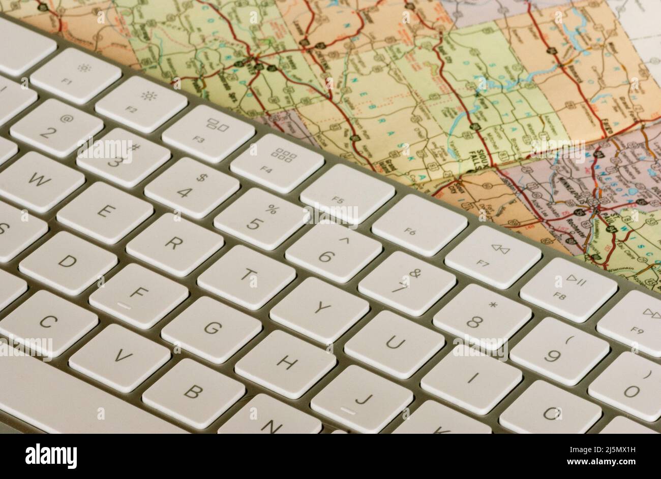 Clavier d'ordinateur de plus près avec carte papier montrant les villes et les itinéraires de voyage. Banque D'Images