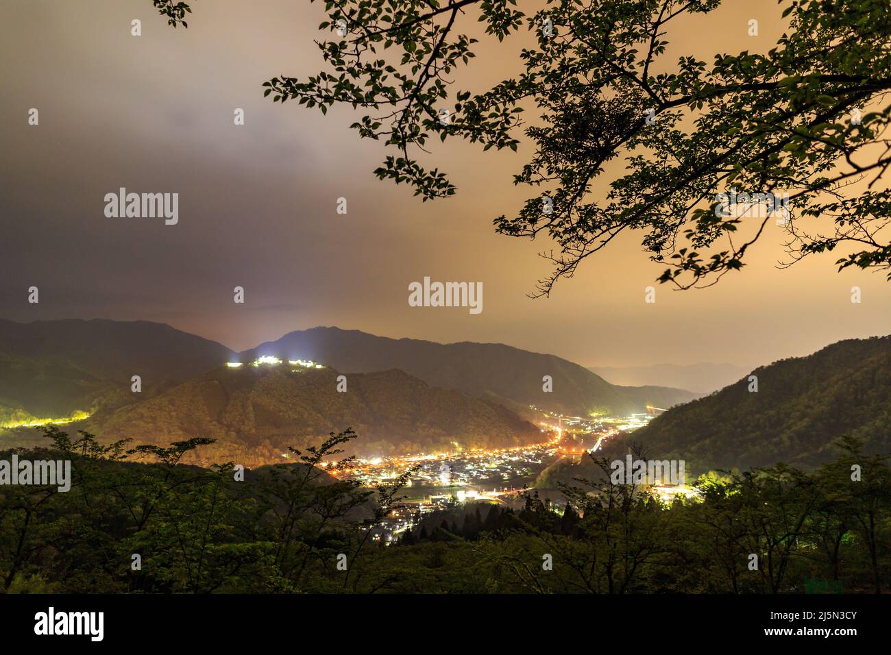 Lumières du petit village de montagne sous les nuages la nuit Banque D'Images