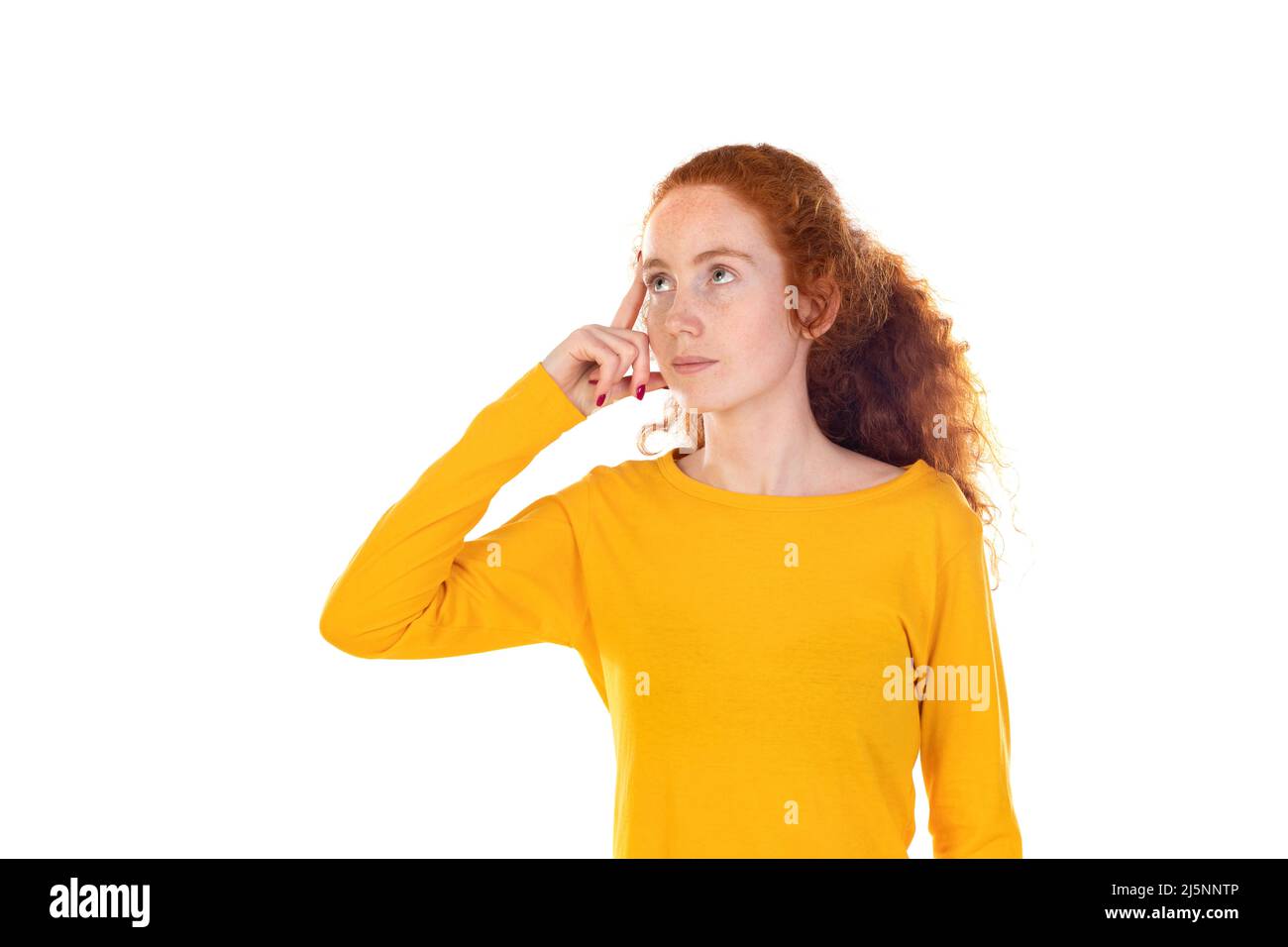 Portrait d'une fille à tête rouge pensive portant un t-shirt jaune isolé sur fond blanc de studio. Banque D'Images