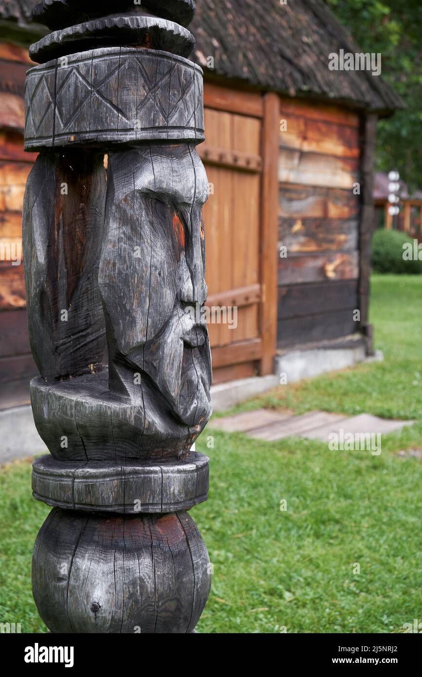 Poste de Hitching sur fond de maison de l'ail. Poteau en bois à lequel un cheval est attaché pour l'empêcher de se départir, sculpté d'une bûche en forme de WO Banque D'Images