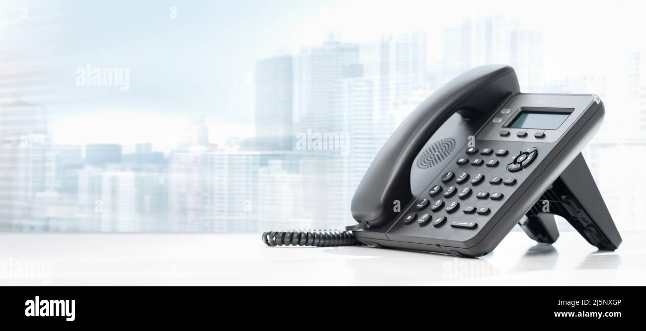 téléphone avec VOIP sur une table blanche sur fond de ville floue. Service clientèle, concept de centre d'appels. appareils téléphoniques au bureau. Moderne Banque D'Images
