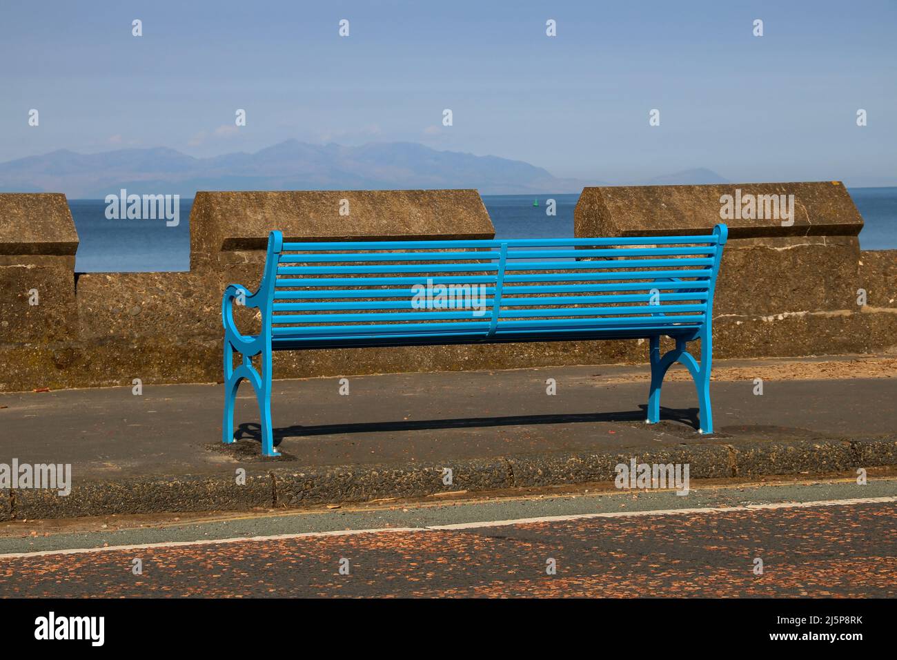 Banquette peinte en bleu faisant face à l'île d'Arran sur une esplanade côtière Banque D'Images