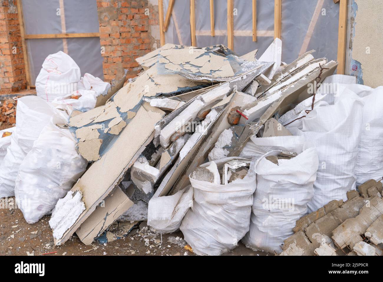 Débris de construction provenant du revêtement de façade démonté. Déchets de construction dans des sacs blancs dans la rue Banque D'Images
