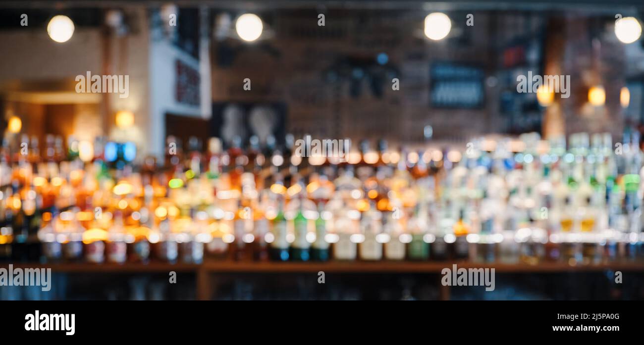 Fond de bar ou de pub avec bouteilles de liqueur floues sur les étagères. Banque D'Images