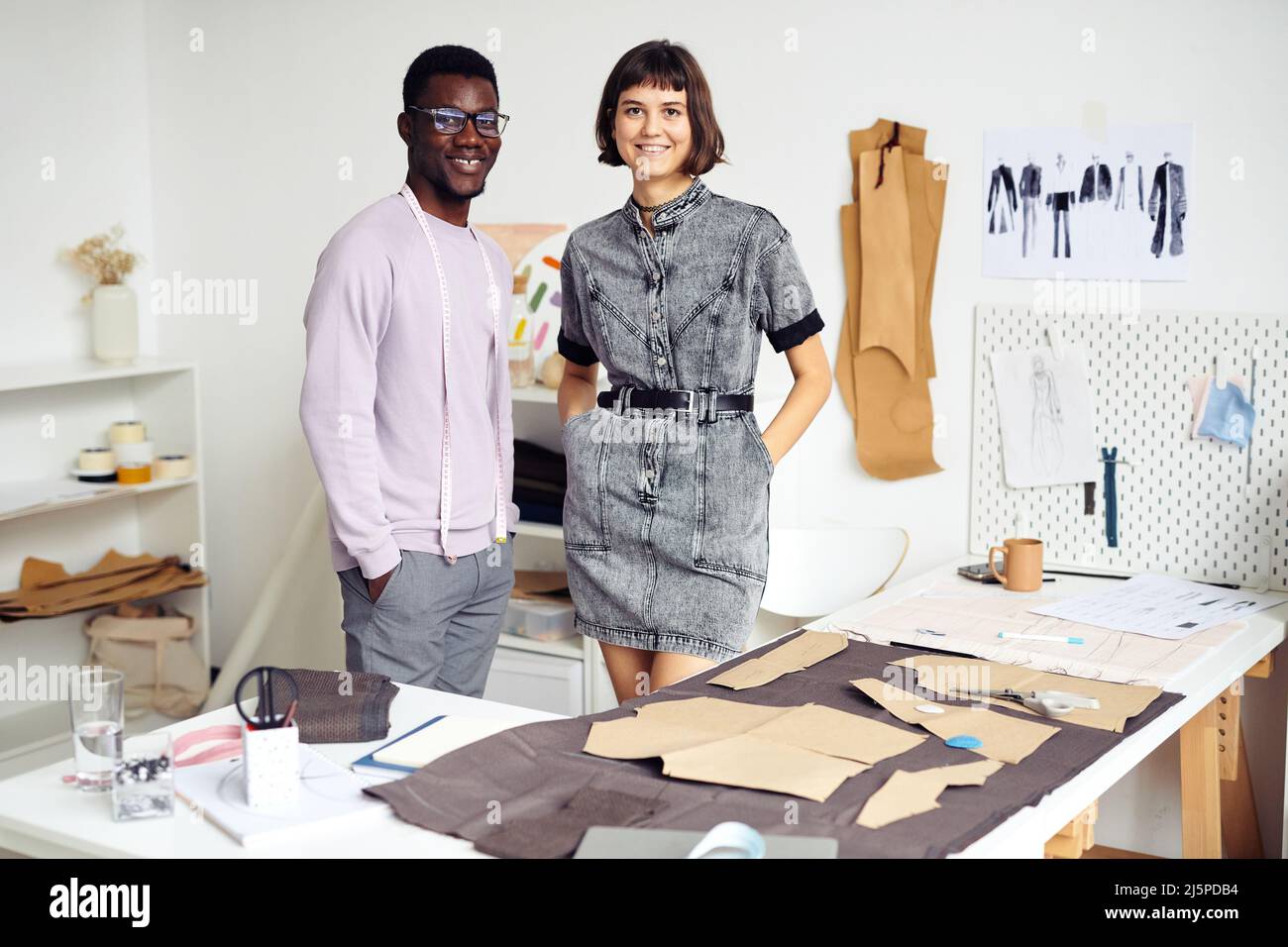 Une équipe multi-ethnique souriante de jeunes créateurs de mode travaillant sur un grand projet en atelier ou en studio Banque D'Images