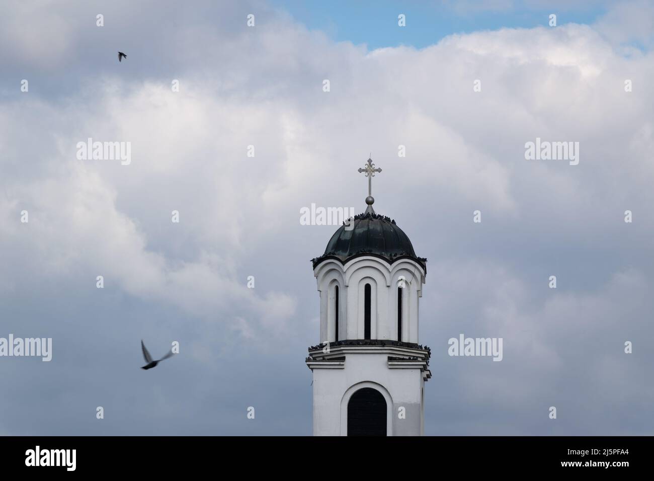 Troupeau de pigeons en se reposant sur le clocher de l'église, deux oiseaux en vol Banque D'Images
