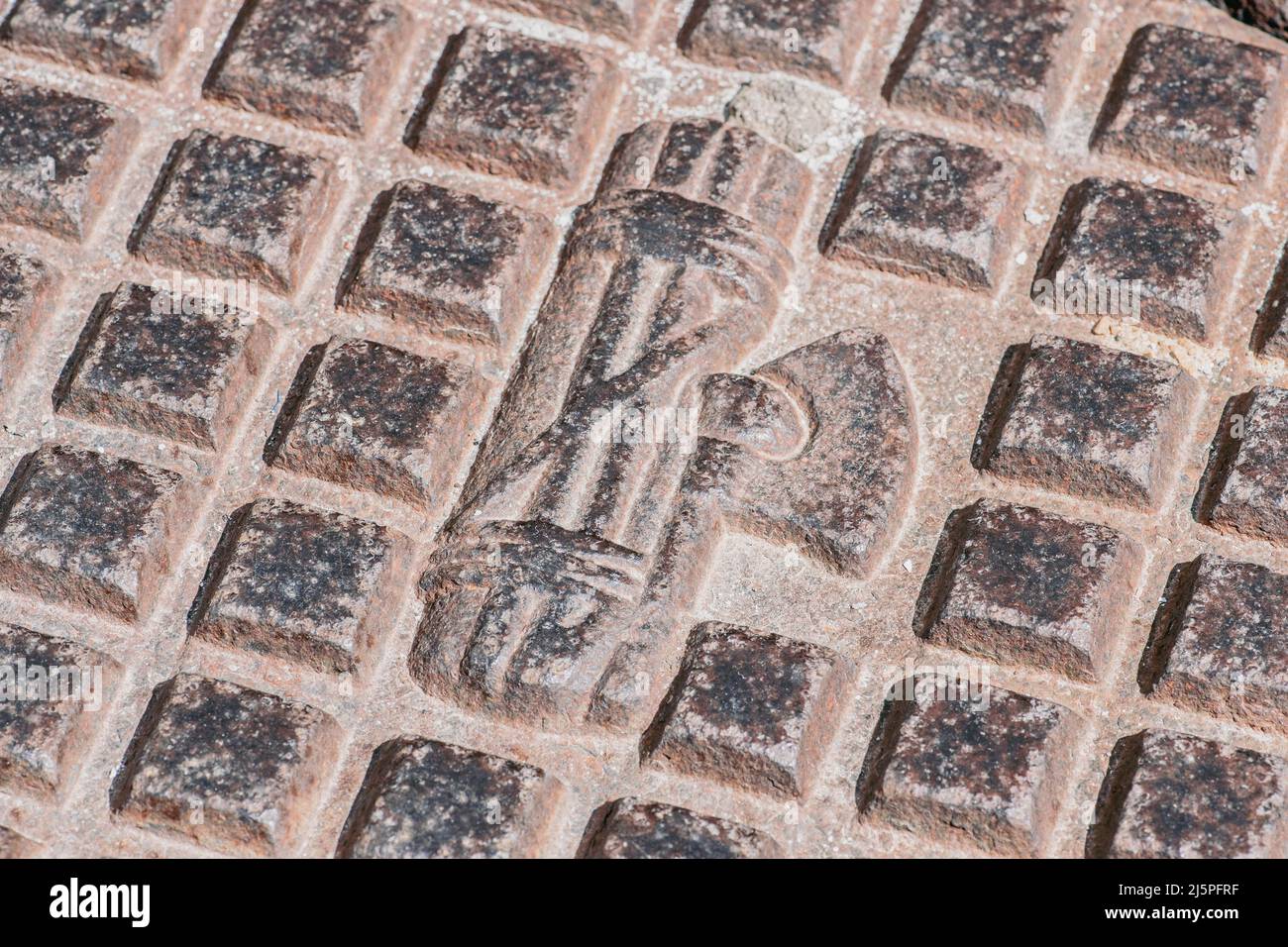 Symbole du fascisme délavé sur un trou d'eau ou d'égout, Mottola, Puglia, Italie Banque D'Images