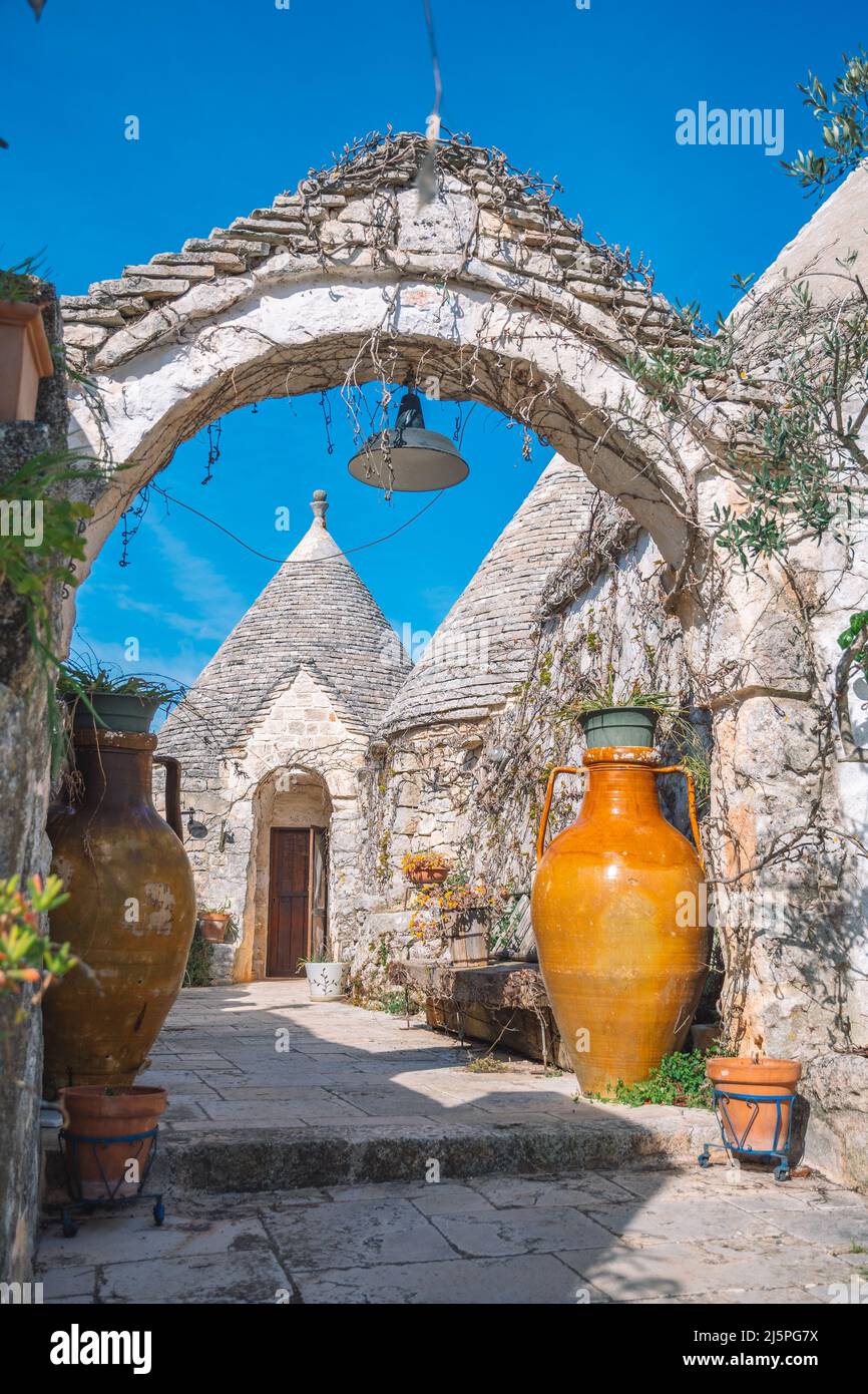 Belle maison Trulli ou Trullo, cabane traditionnelle en pierre sèche des Pouilles avec toit conique et ancienne arche en pierre sèche et murs à Puglia, Italie avec grand vase Banque D'Images
