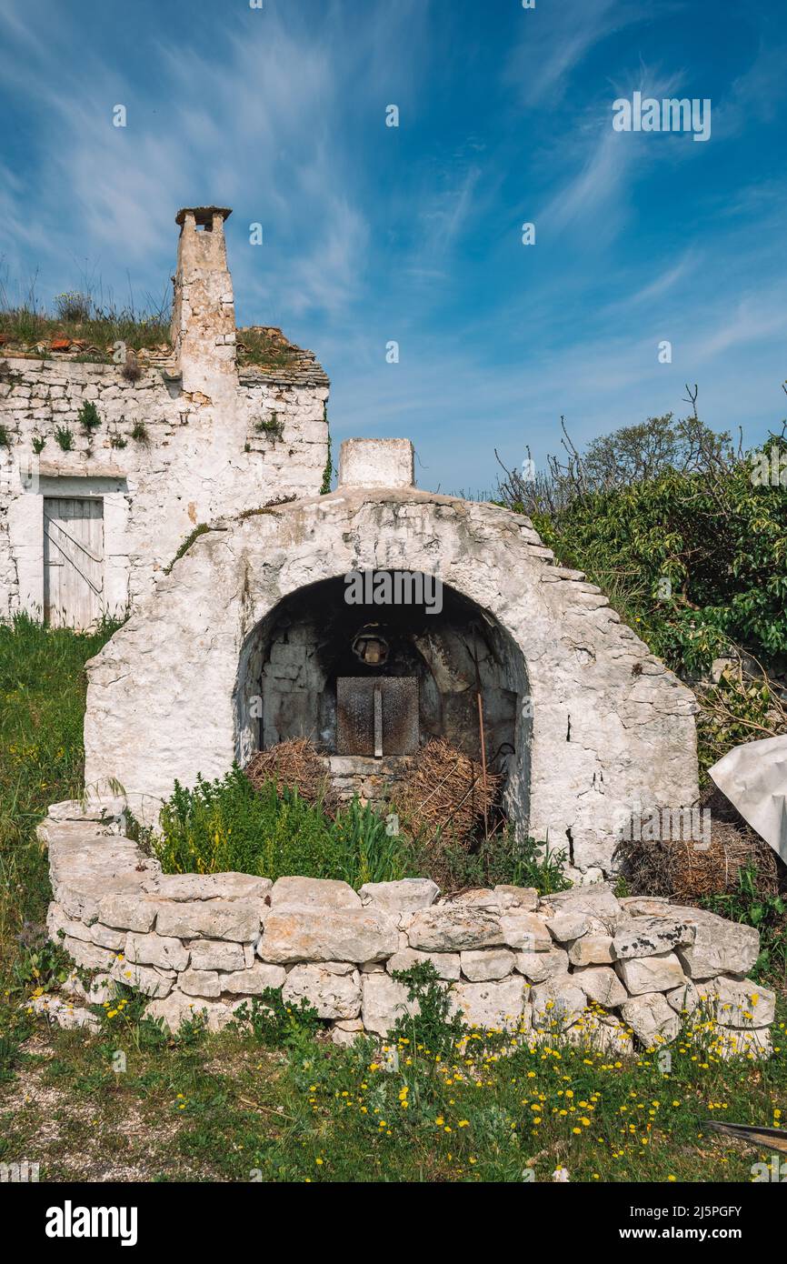 Beau blanc traditionnel vieux four ou cheminée en pierre dans la campagne dans la région de Puglia, Italie avec mur de pierre sèche et la nature autour Banque D'Images