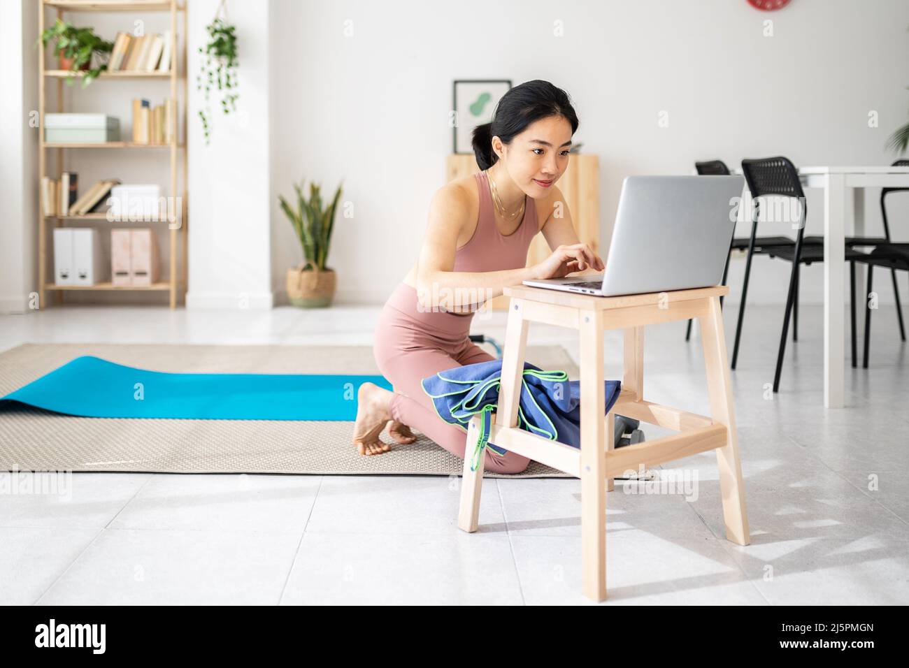 Professeur de yoga asiatique préparant un cours virtuel à la maison lors d'une vidéoconférence. Banque D'Images