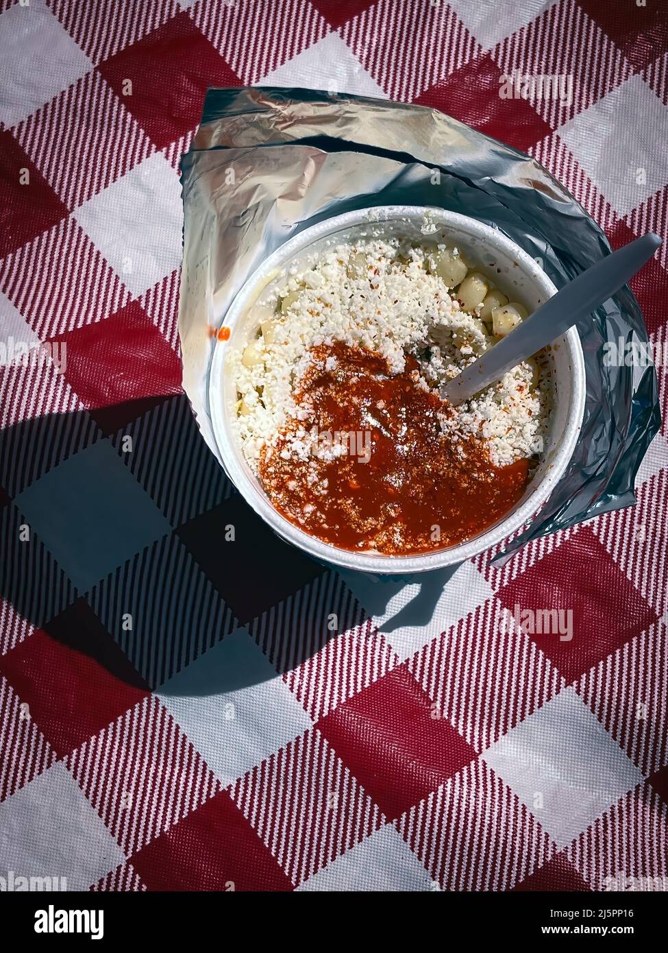 Une vue vers le bas à une délicieuse tasse de ELOTE, le maïs stréen mexicain, à l'intérieur d'une tasse de styromousse enveloppée dans du papier d'aluminium dans un marché agricole d'El Paso. Banque D'Images