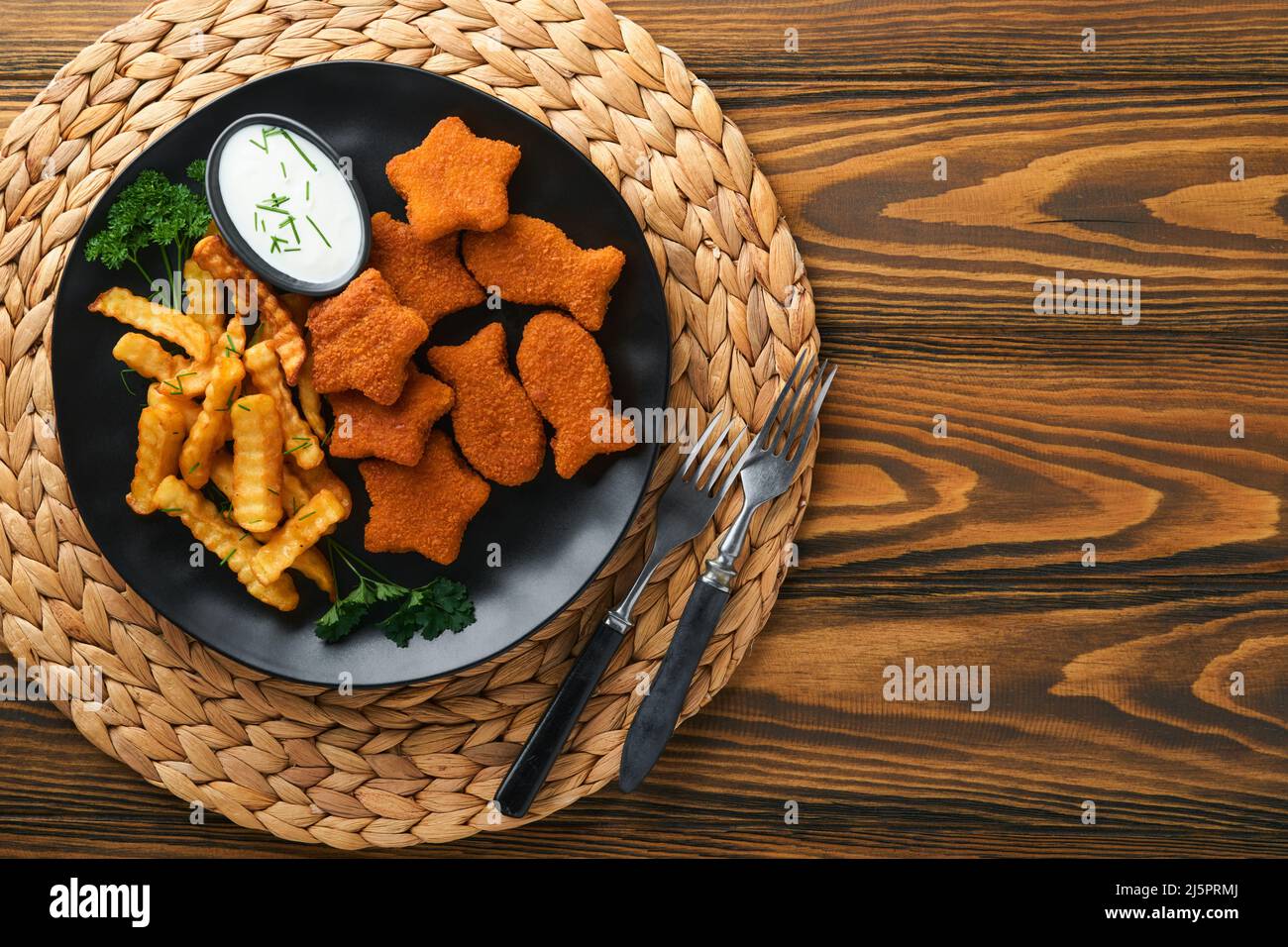 Fish and Chips, restauration rapide britannique. Bâtonnets de poisson avec frites sur plaque noire sur fond de table en bois. Plat traditionnel britannique authentique Banque D'Images