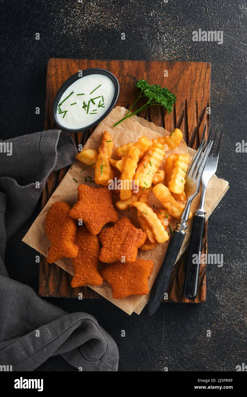 Fish and Chips, restauration rapide britannique. Bâtonnets de poisson avec frites sur un panneau rustique sur fond de vieux béton foncé. Traditionnelle britannique authentique str Banque D'Images