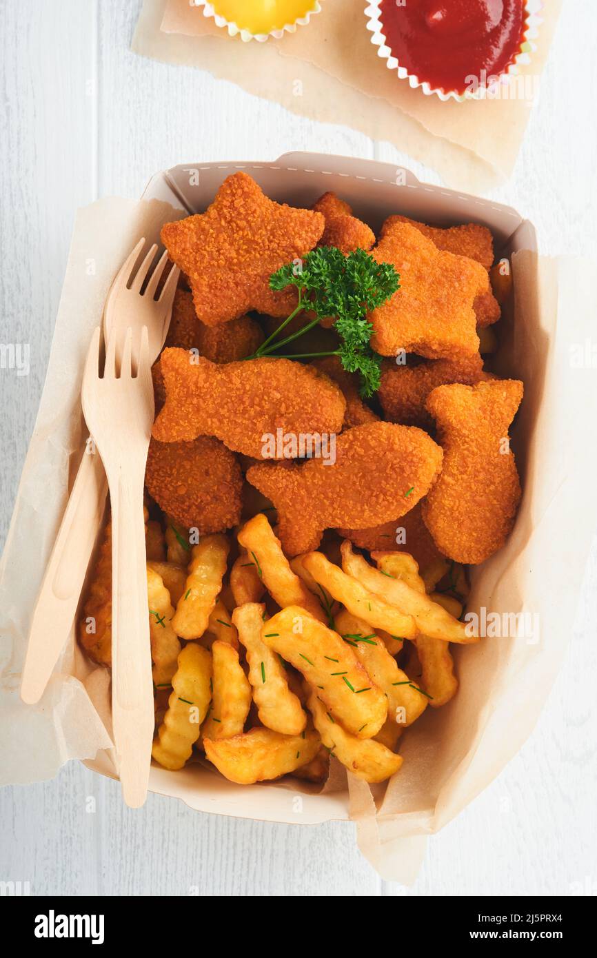 Fish and Chips, restauration rapide britannique. Bâtonnets de poisson avec frites sur une assiette en papier à emporter sur fond en bois blanc. Authentique britannique traditionnel Banque D'Images