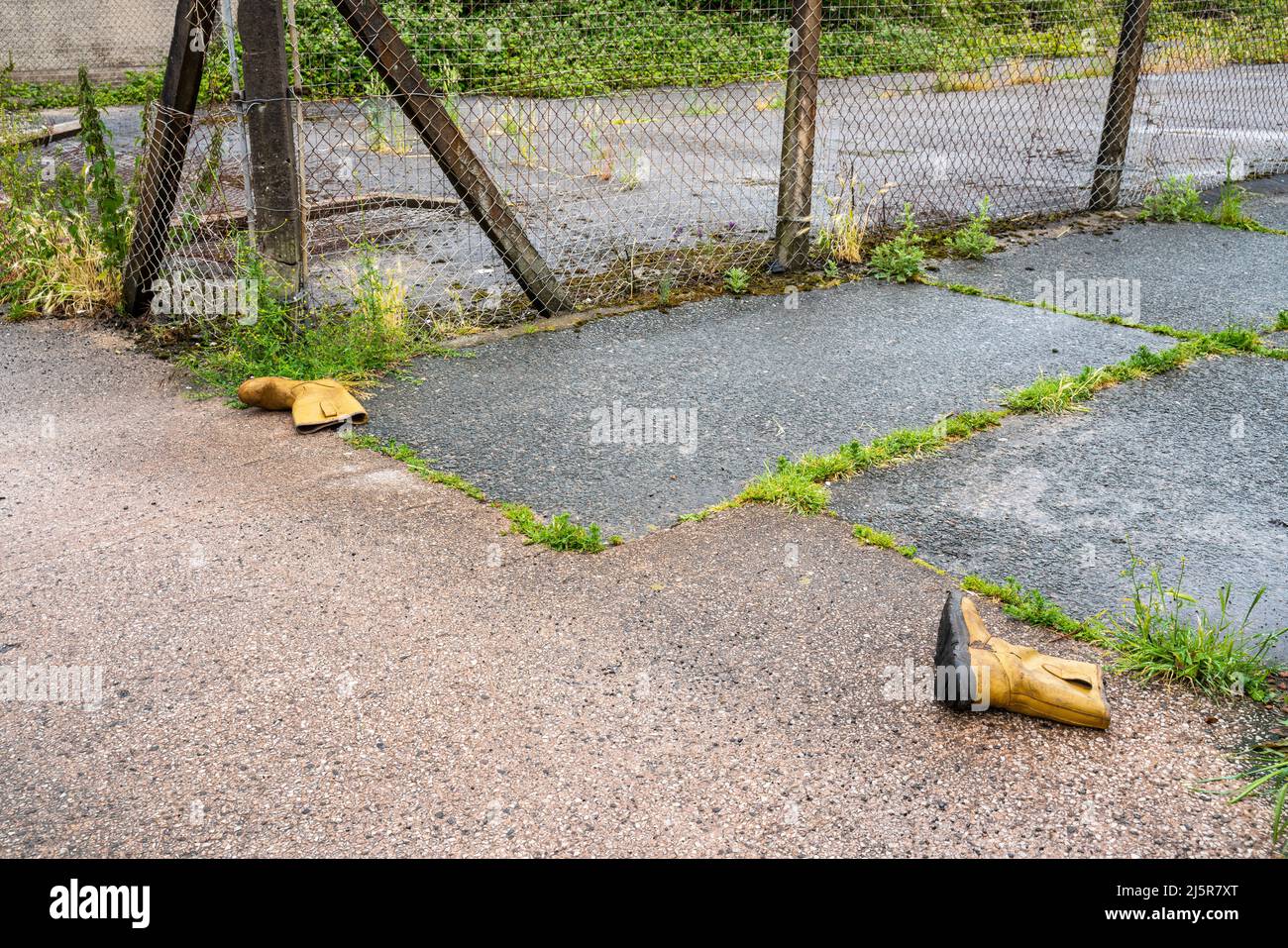 Paire de bottes de manutention jaunes jetées dans la rue arrière de la ville Banque D'Images