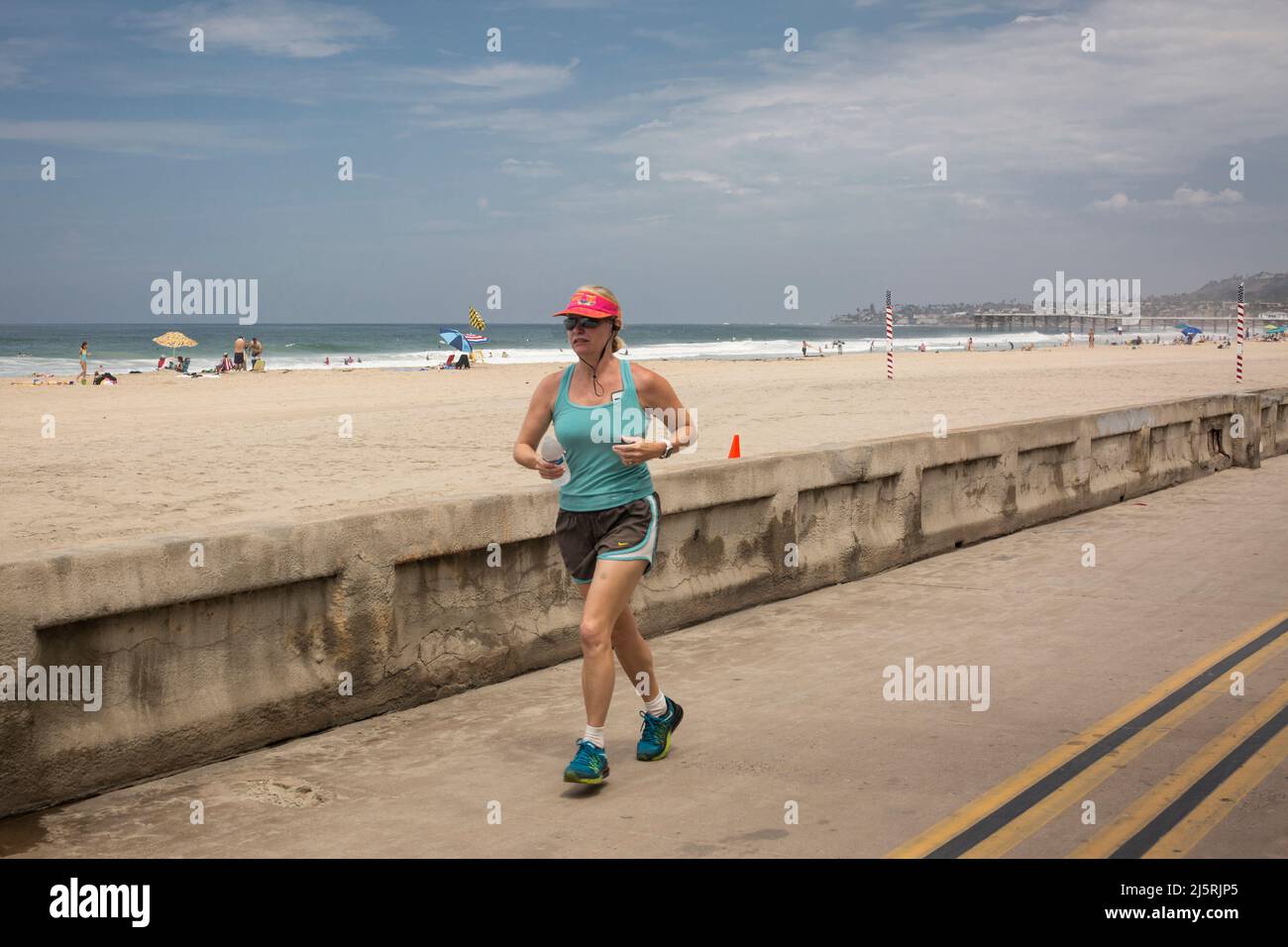 Femme qui court sur la plage sur Ocean front Walk à Mission Bay, San Diego Banque D'Images