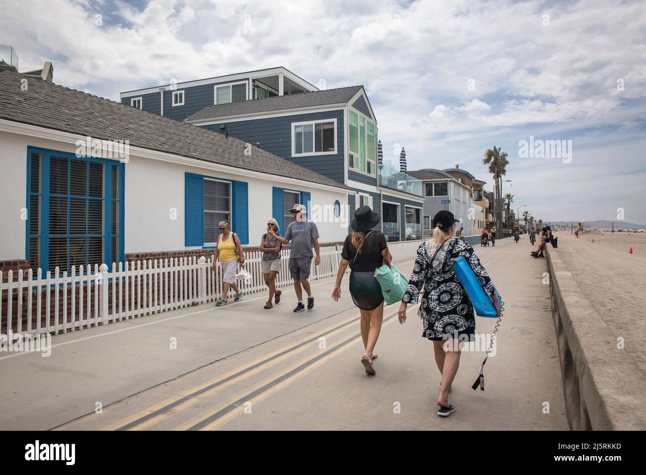 Quelques touristes se promenant sur l'océan promenade en face de quelques maisons de vacances d'été, Mission Bay, San Diego Banque D'Images