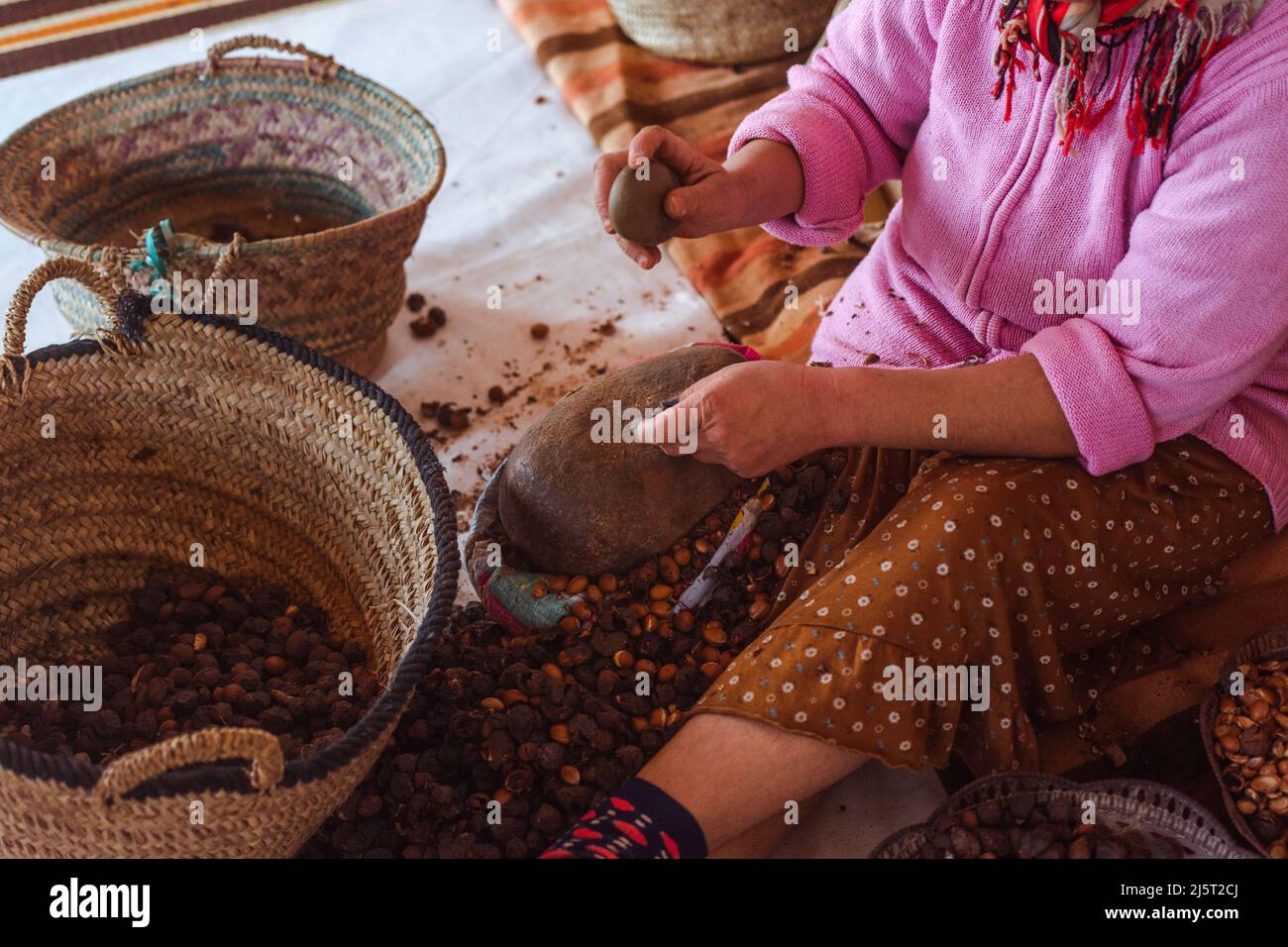 Femme brisant des graines d'argan en utilisant un rocher pour faire du pétrole, dans une coopérative au Maroc, de vrais gens faisant des choses réelles. La culture Banque D'Images