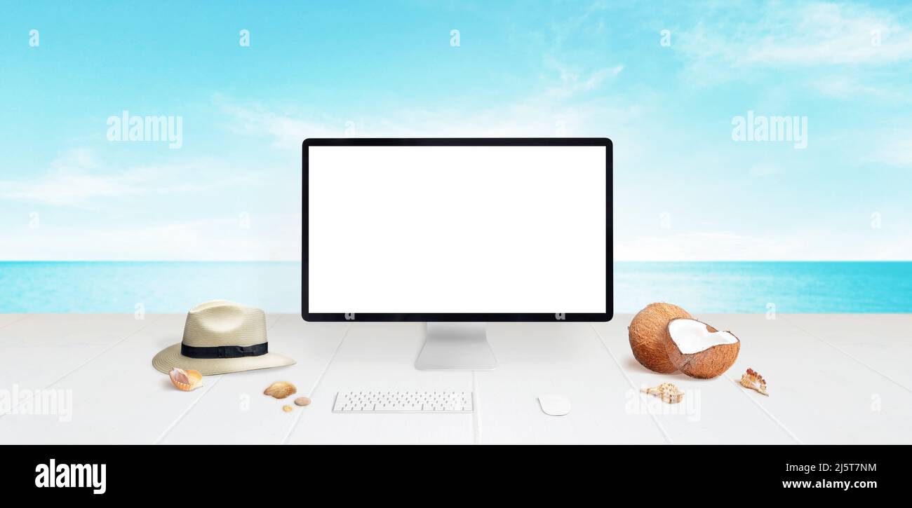 Maquette d'ordinateur sur le bureau avec plage en arrière-plan. Écran isolé pour maquette. Chapeau de voyageur, noix de coco et coquillages à côté. Concept de voyage Banque D'Images