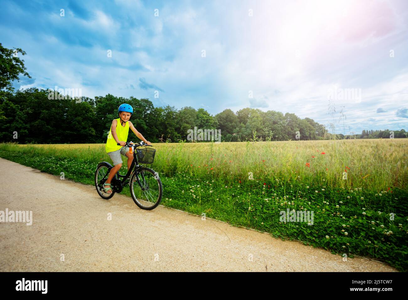 Un jeune garçon fait un vélo dans le parc près du champ Banque D'Images