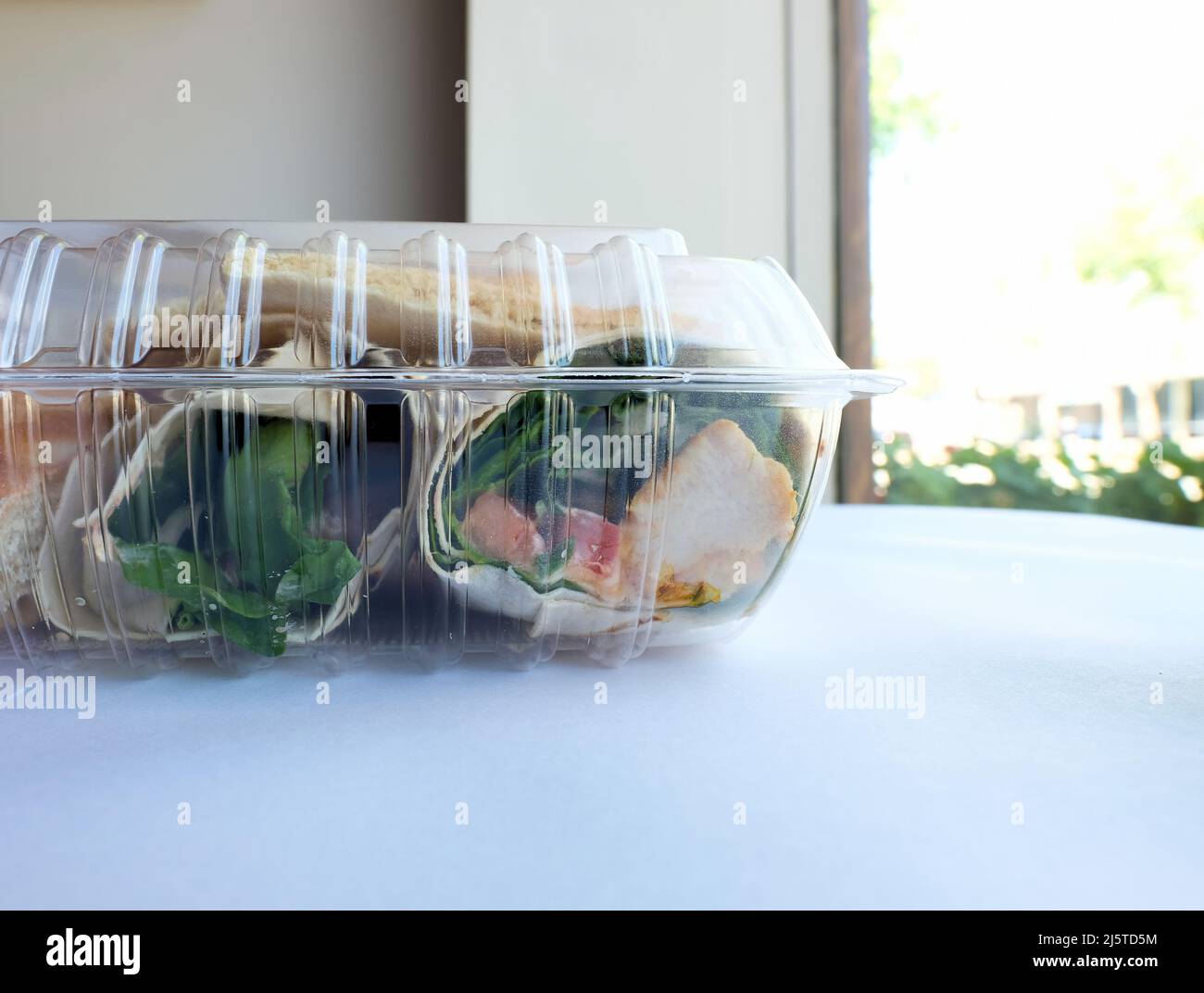 Contenant de résidus en plastique transparent avec un poulet et un emballage d'houmous restant après un repas au restaurant ; repas à emporter en boîte ou emballé. Banque D'Images
