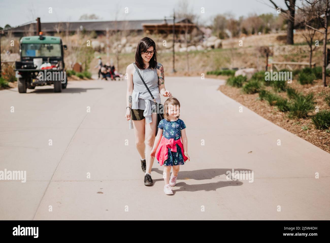 Mère et fille marchent le long du trottoir au zoo le jour de l'été Banque D'Images