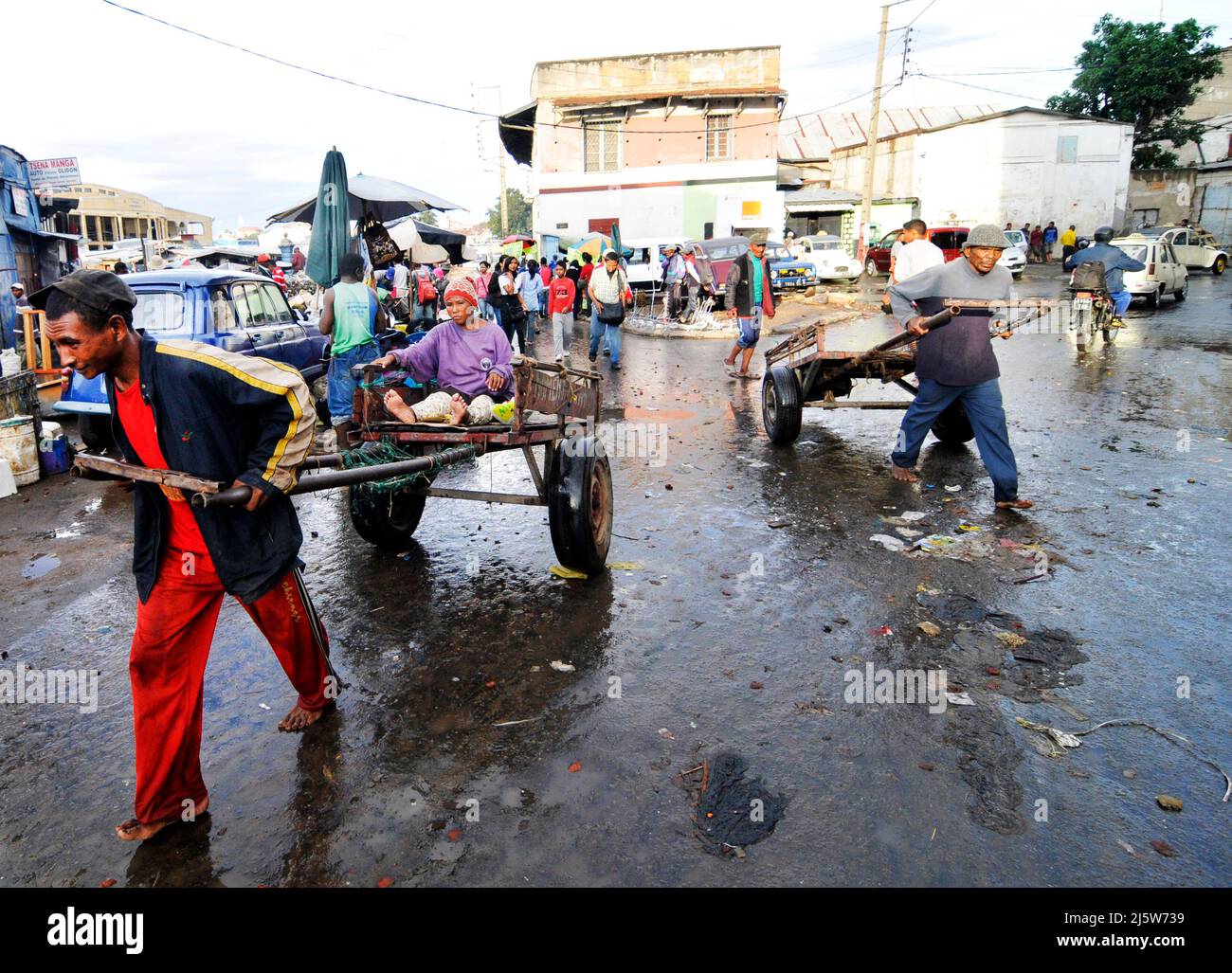 Un homme malgache tirant une voiturette dans un marché coloré à Antananarivo, Madagascar. Banque D'Images