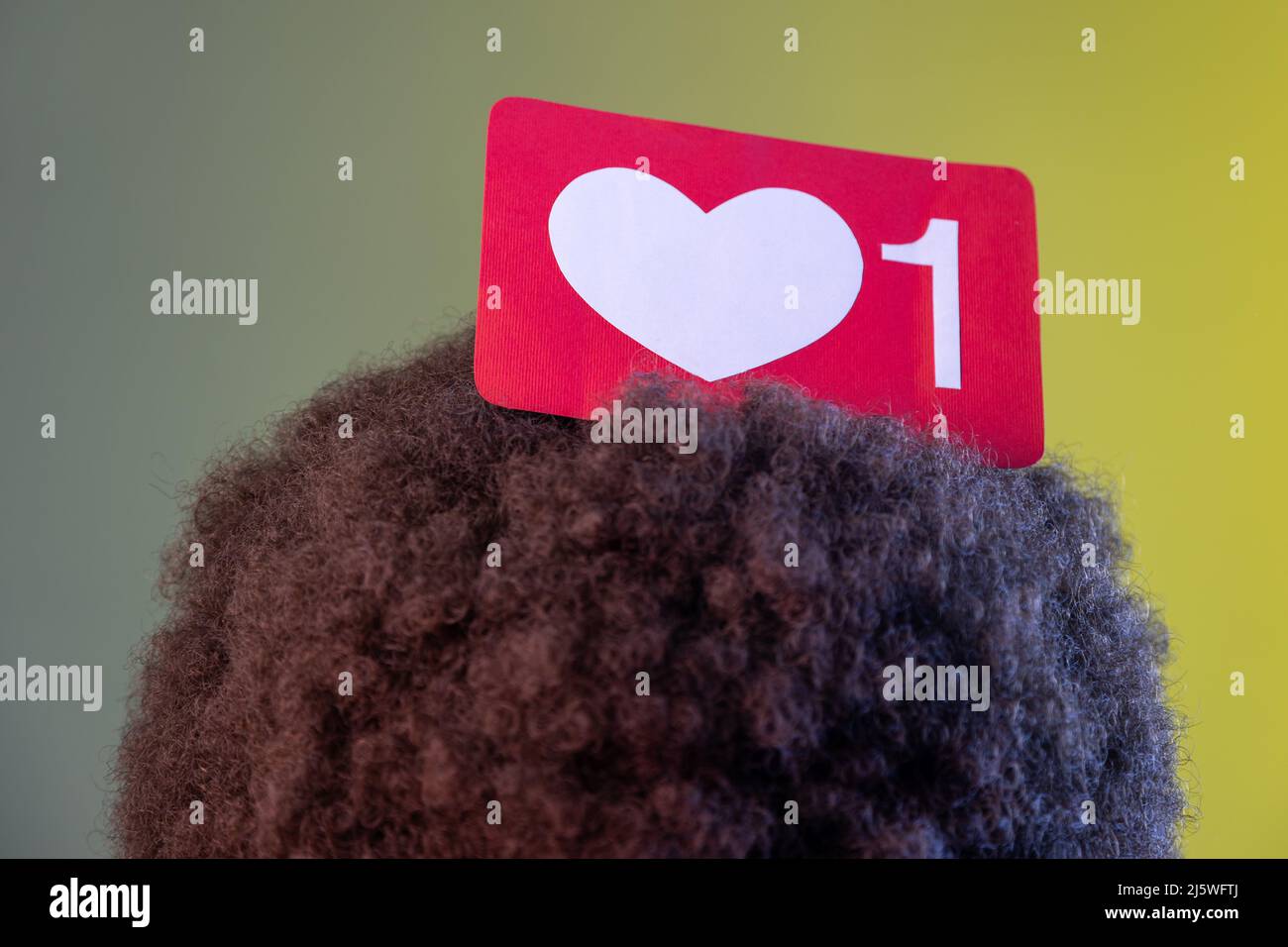 Gros plan de la personne inconnue anonyme avec la coiffure afro posant avec le coeur de blogueur sur sa tête, compteur emoji, notification de suiveur. Studio d'intérieur isolé sur fond de néon coloré. Banque D'Images