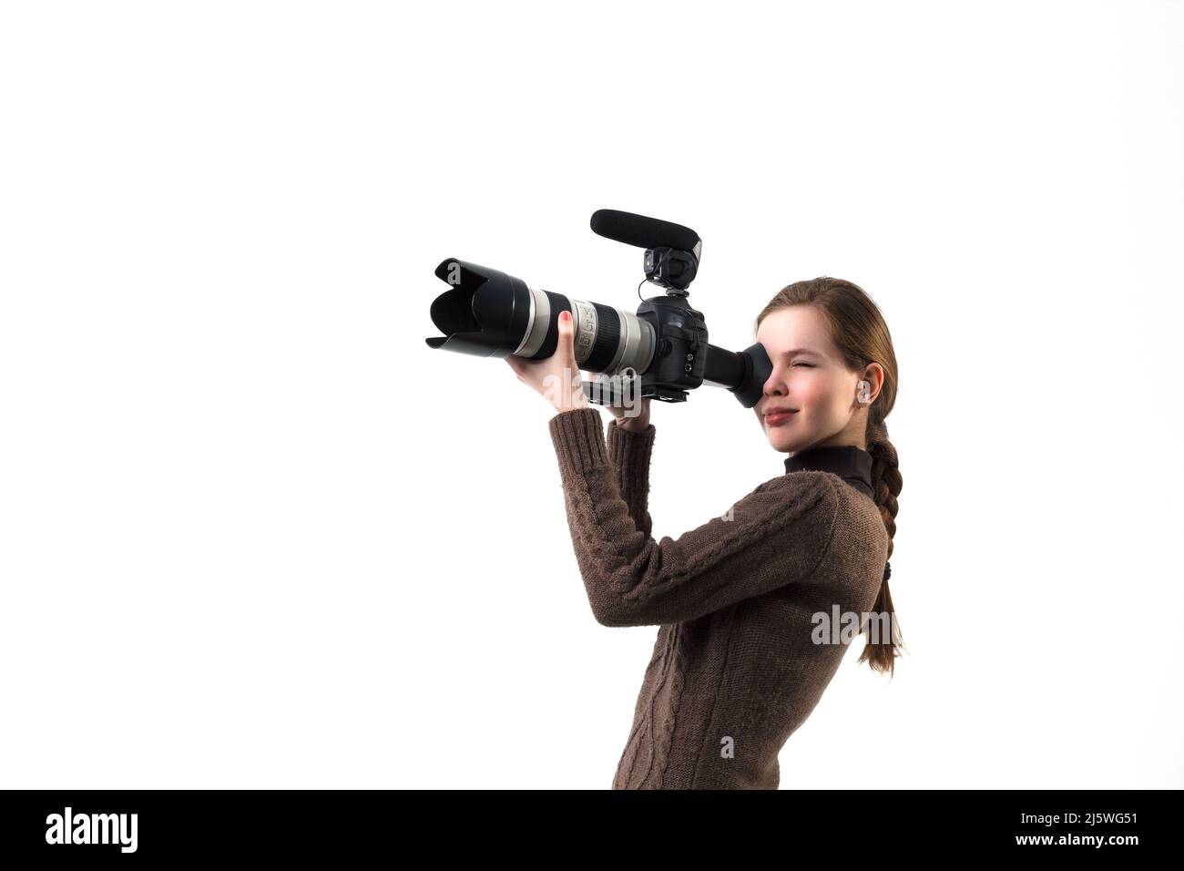 La belle photographe fille avec un appareil photo reflex numérique professionnel posé sur un fond blanc en studio. Apprentissage photo, étude, concept de formation Banque D'Images