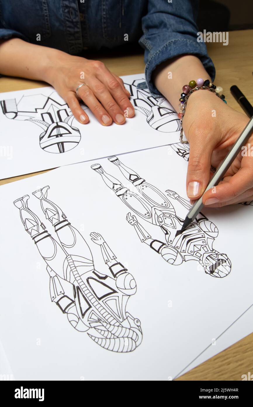 Concept art. L'artiste dessine des croquis de robots cyborg sur papier. Conception de personnages pour un jeu vidéo. Création d'animation. Banque D'Images