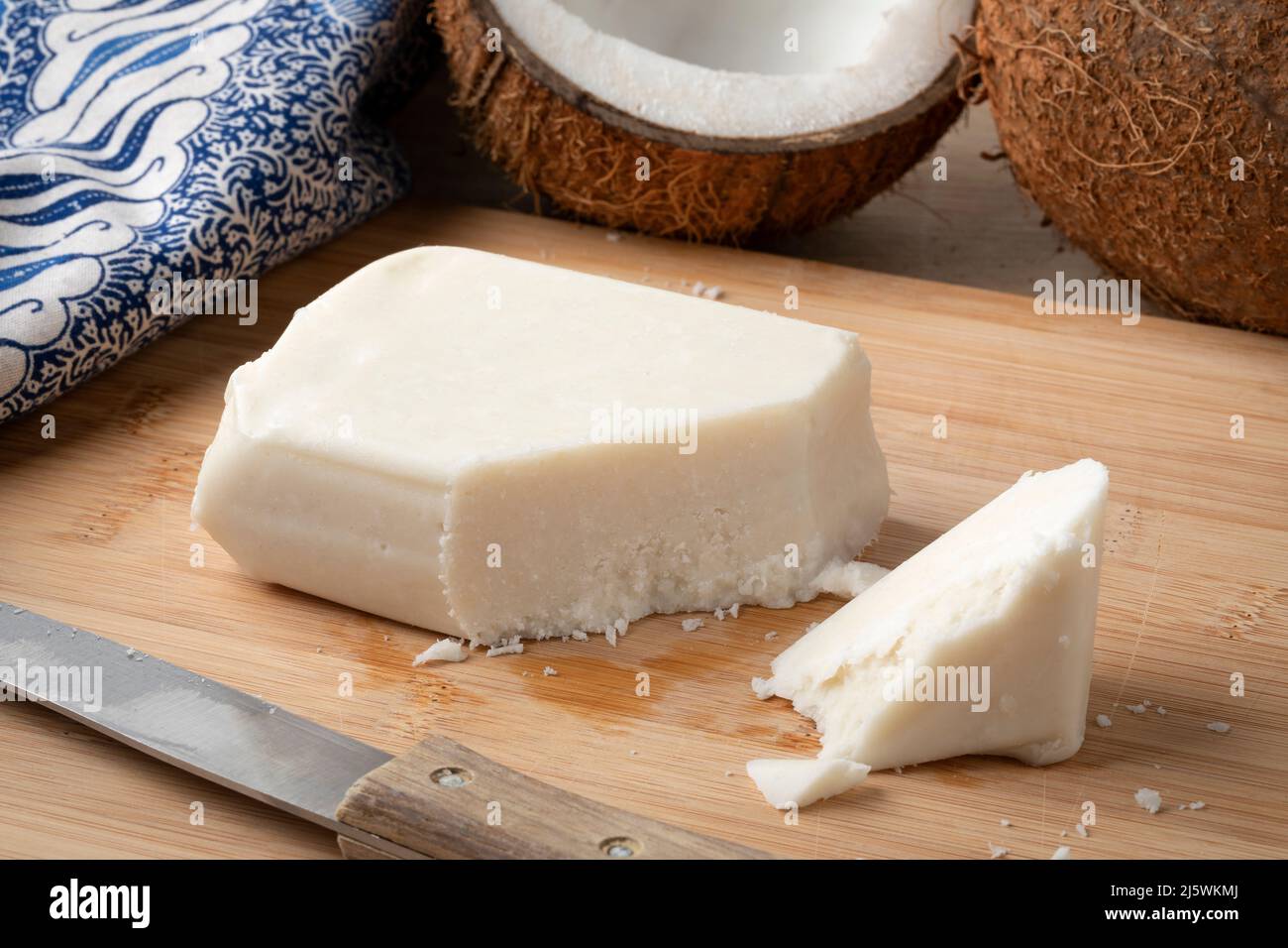 Morceau de noix de coco crémeuse, beurre de coco, sur une planche à découper de près et noix de coco fraîche sur le fond Banque D'Images