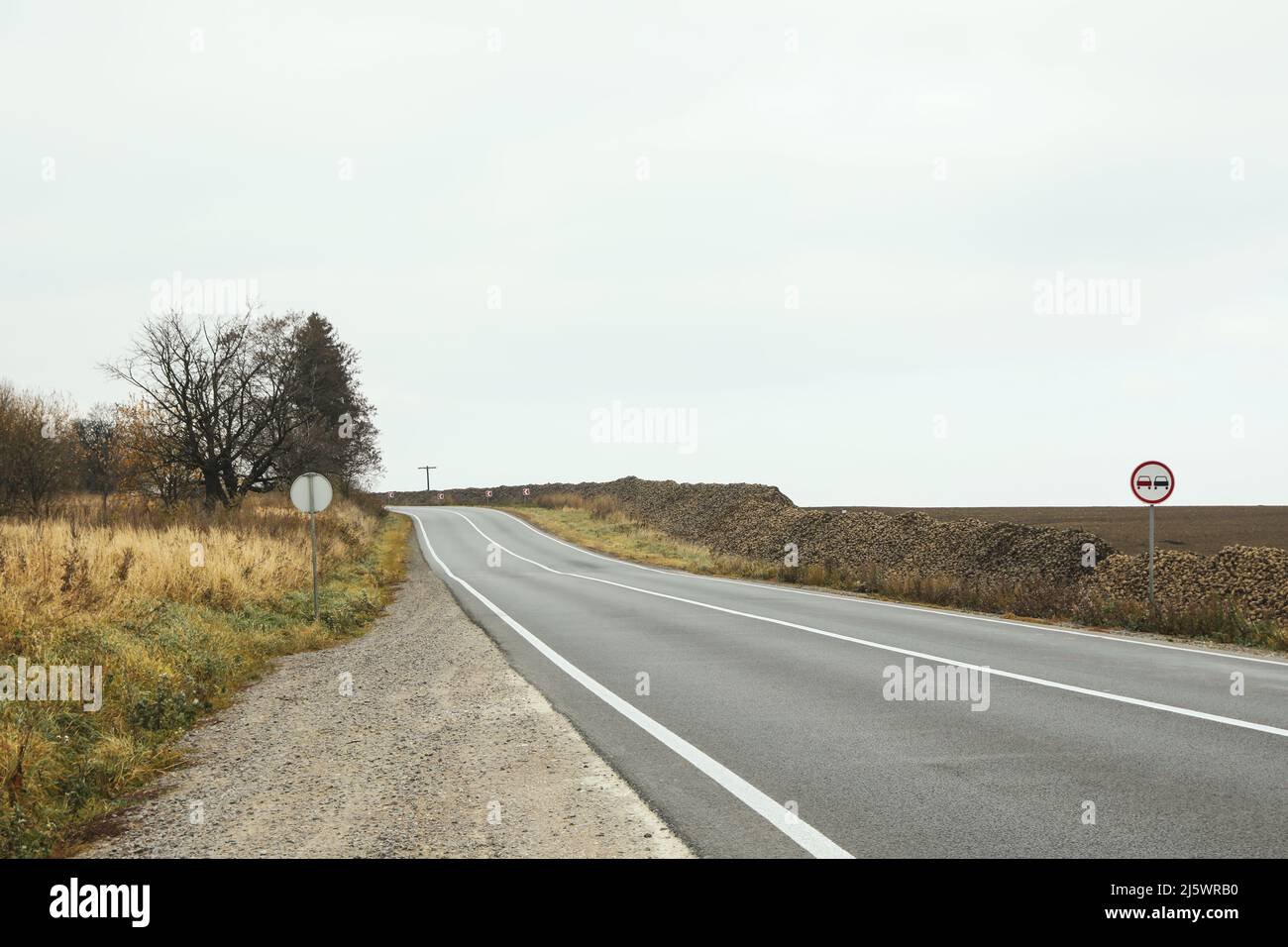 Route et champ de betteraves. Route goudronnée devant un champ avec des tas de betteraves en automne. Route près d'un champ de betteraves Banque D'Images