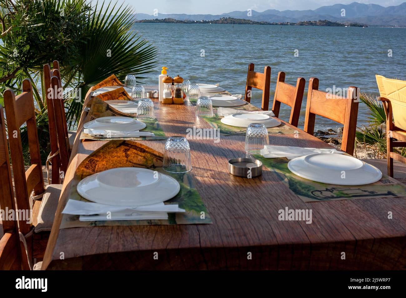 Table servie dans un café au bord de la mer avec assiettes et verres rentrés. Photo horizontale. Banque D'Images