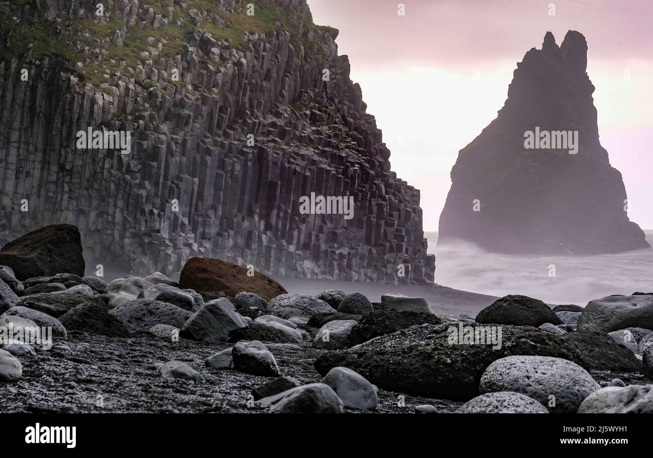 Schwarzer Strand Reynisfjara mit Basaltsäulen, Foto in der Morgendämmerung aufgenommen. Im hintergrund einer der Reynisdrangar-Felsen. Banque D'Images