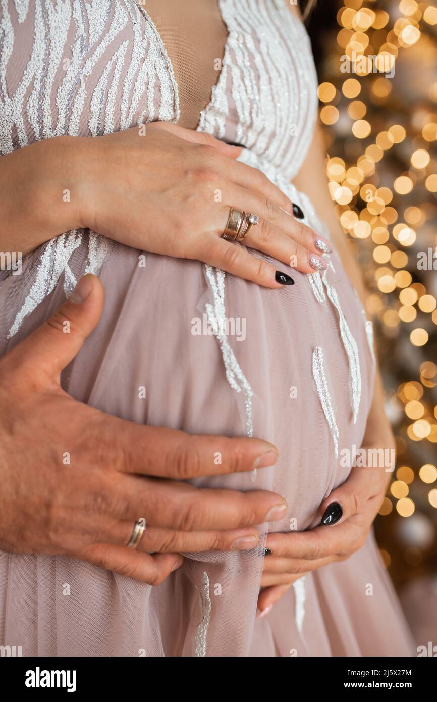 Les mains des hommes et des femmes embrassent le ventre de la fille enceinte. En attente d'un petit miracle Banque D'Images