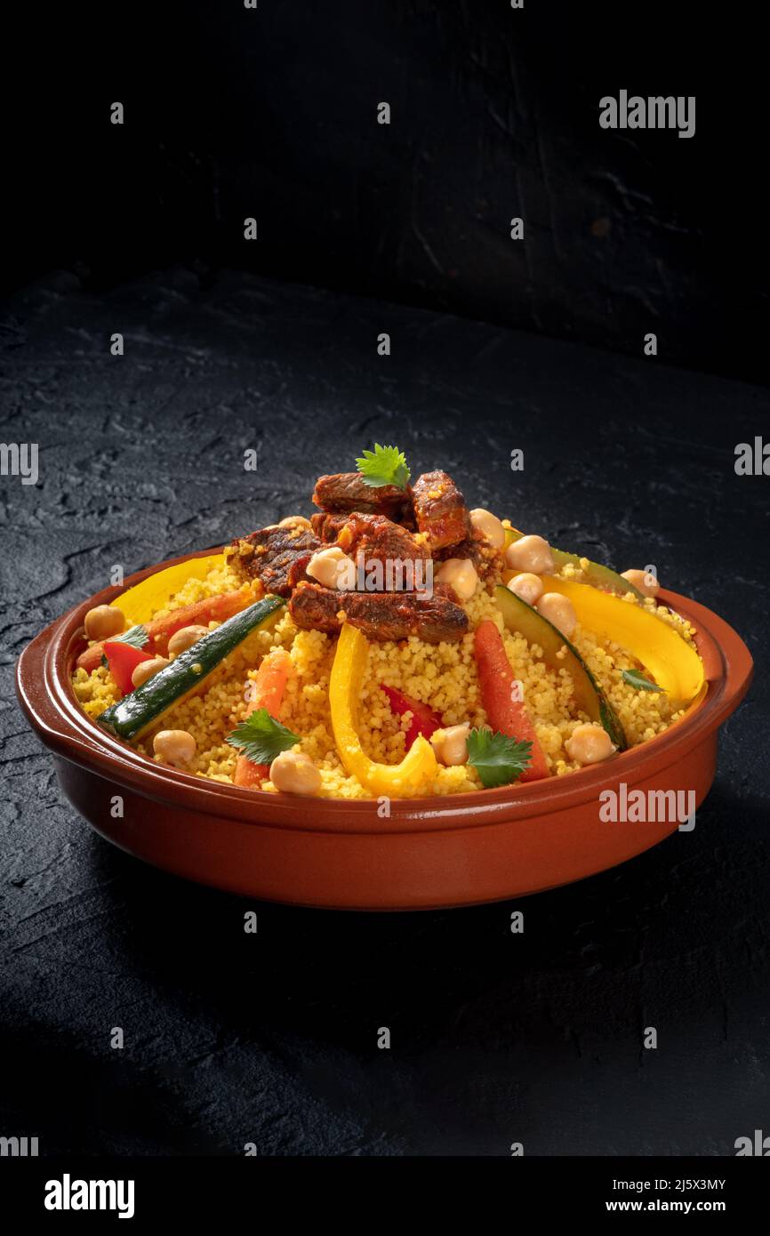 Couscous à la viande et aux légumes, cuisine arabe traditionnelle, sur fond d'ardoise noire Banque D'Images