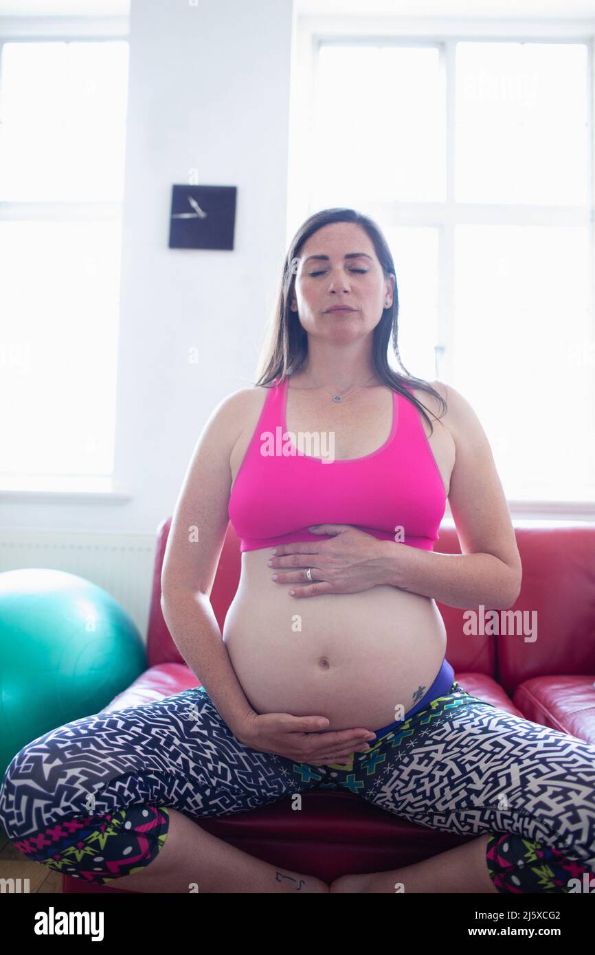 Femme enceinte sereine méditant et tenant la bosse de bébé Banque D'Images