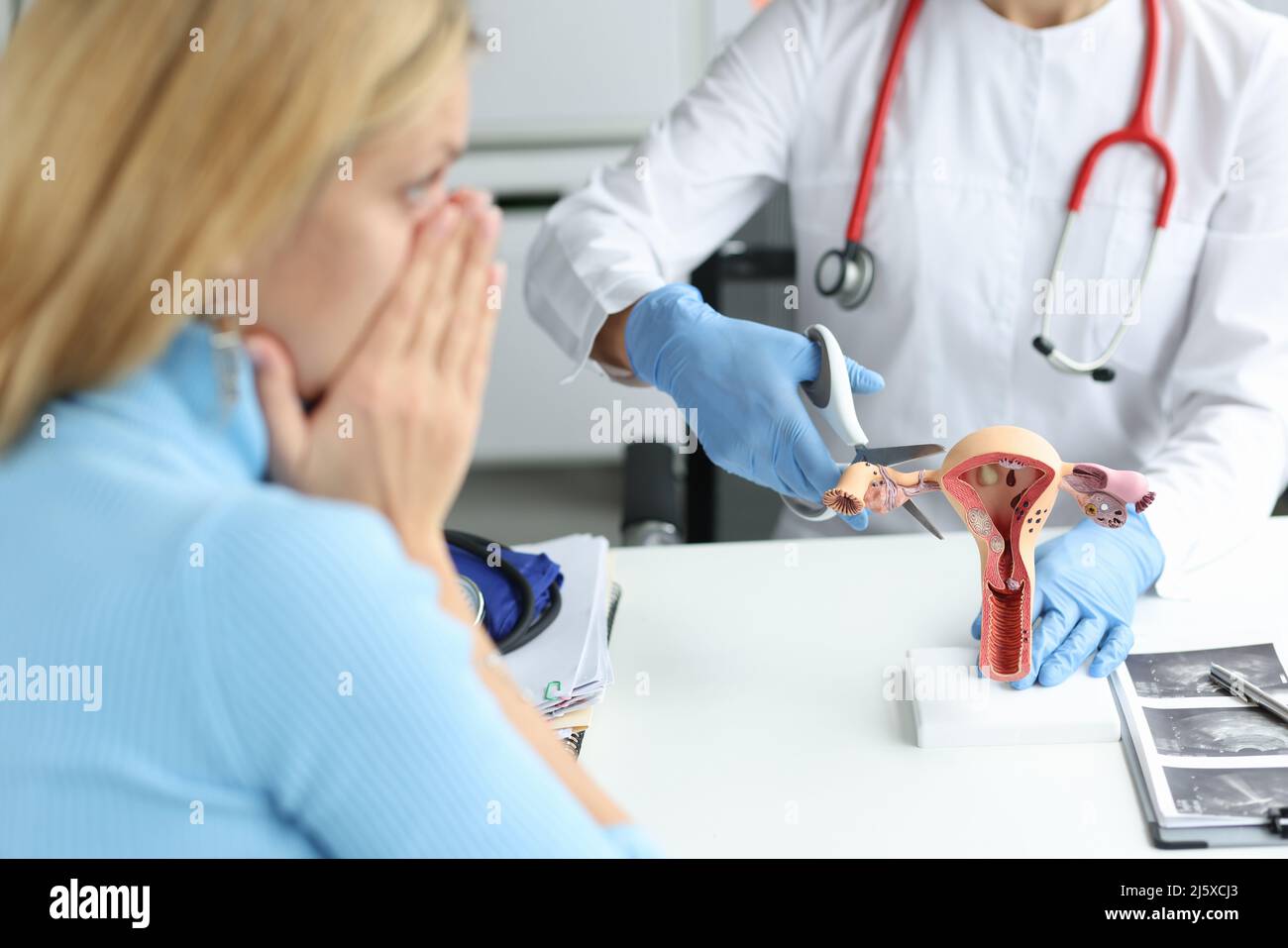 Médecin grimpant tube de Fallope avec des ciseaux sur des modèles artificiels sur l'utérus et les ovaires en clinique Banque D'Images