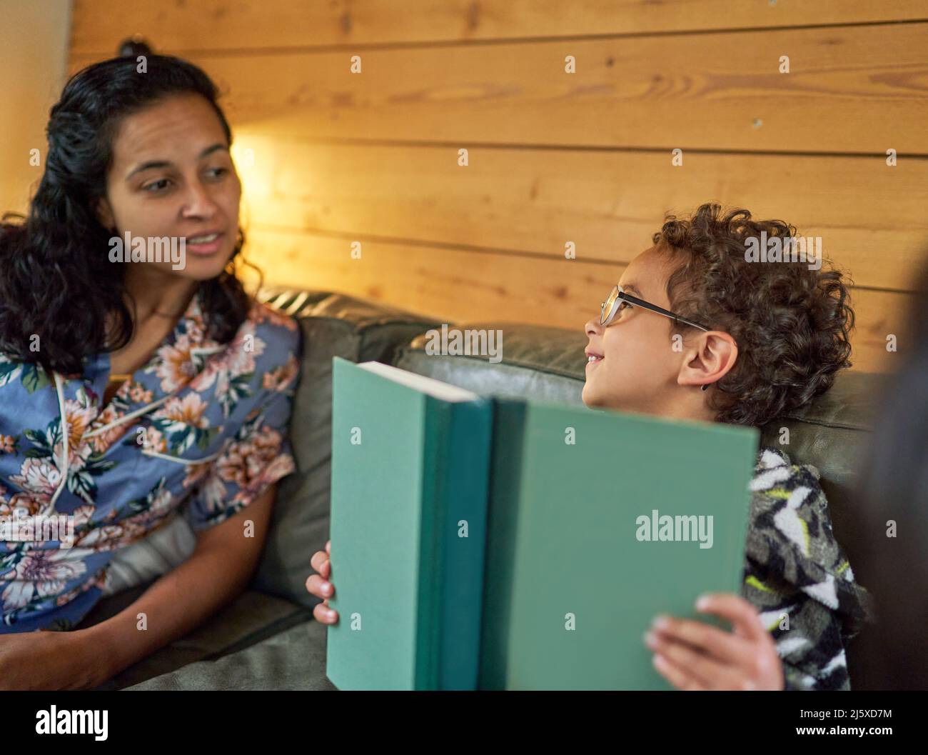 Mère parlant à son fils avec livre sur le canapé Banque D'Images