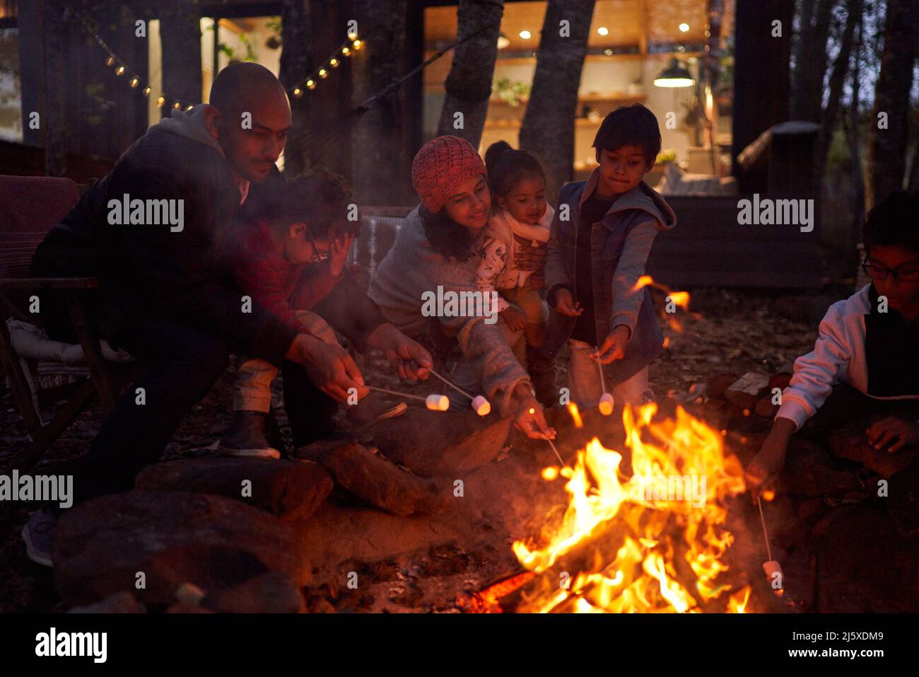Guimauves de toasting en famille au feu de camp à l'extérieur de la cabine Banque D'Images