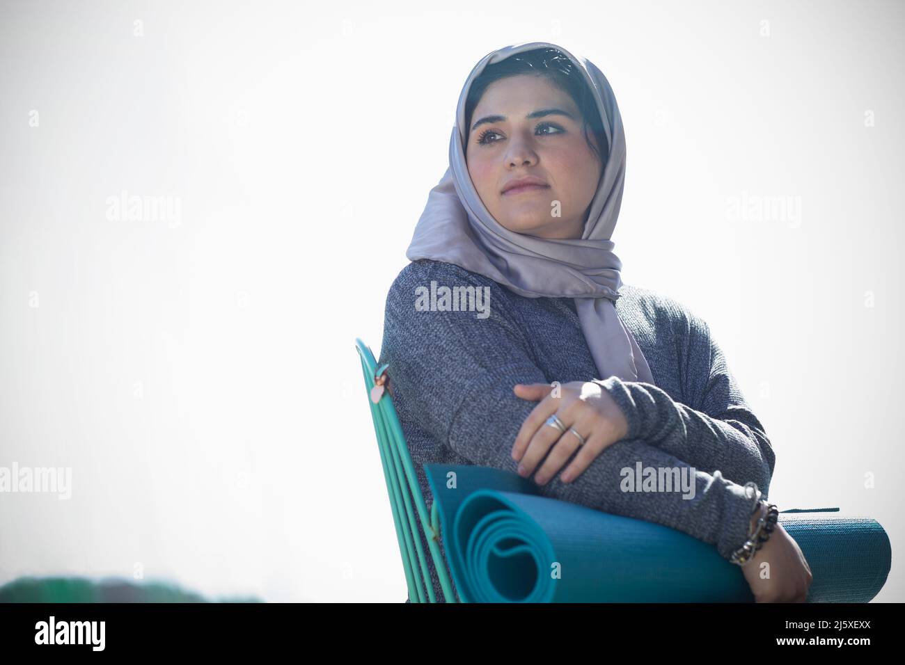 Jeune femme réfléchie en hijab avec tapis de yoga Banque D'Images