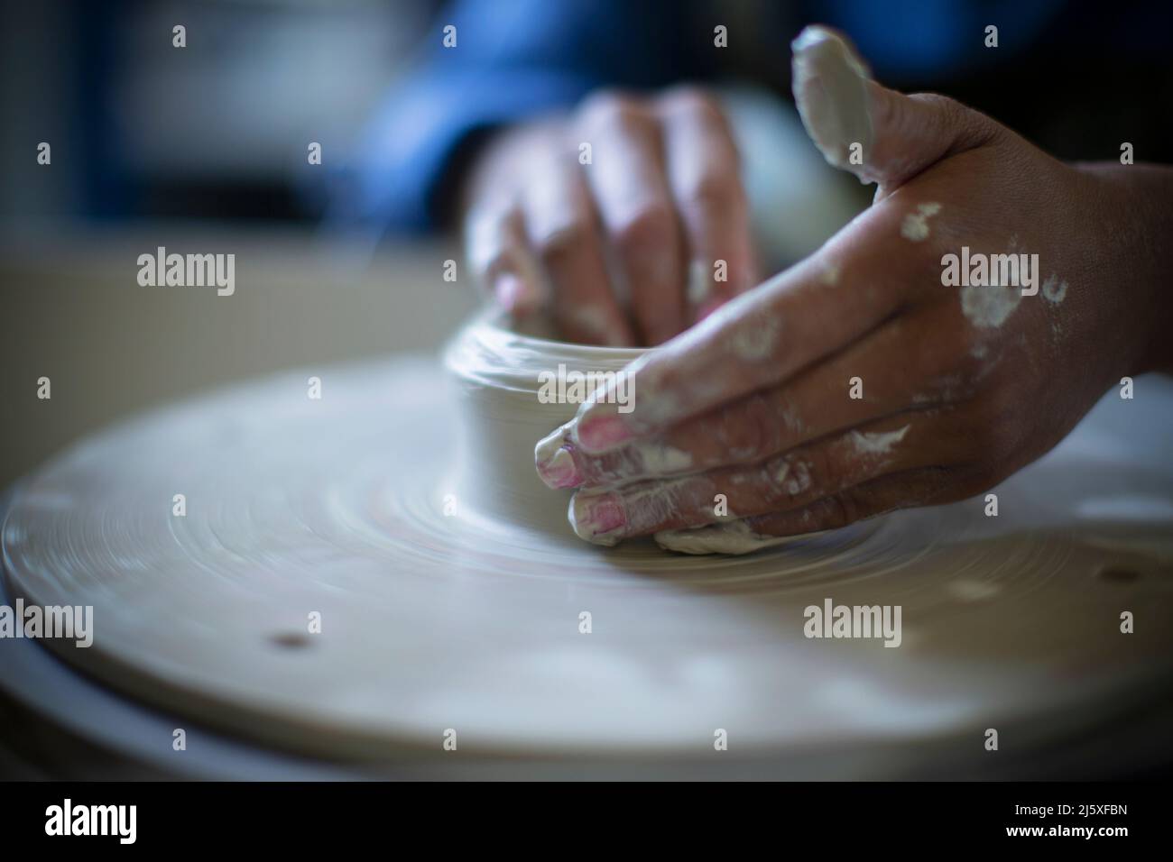 Gros plan des mains de la femme utilisant la roue de poterie Banque D'Images
