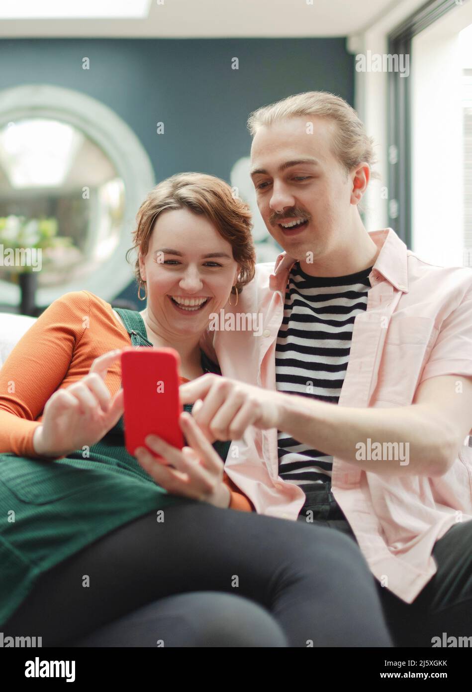 Un jeune couple heureux avec un smartphone à la maison Banque D'Images