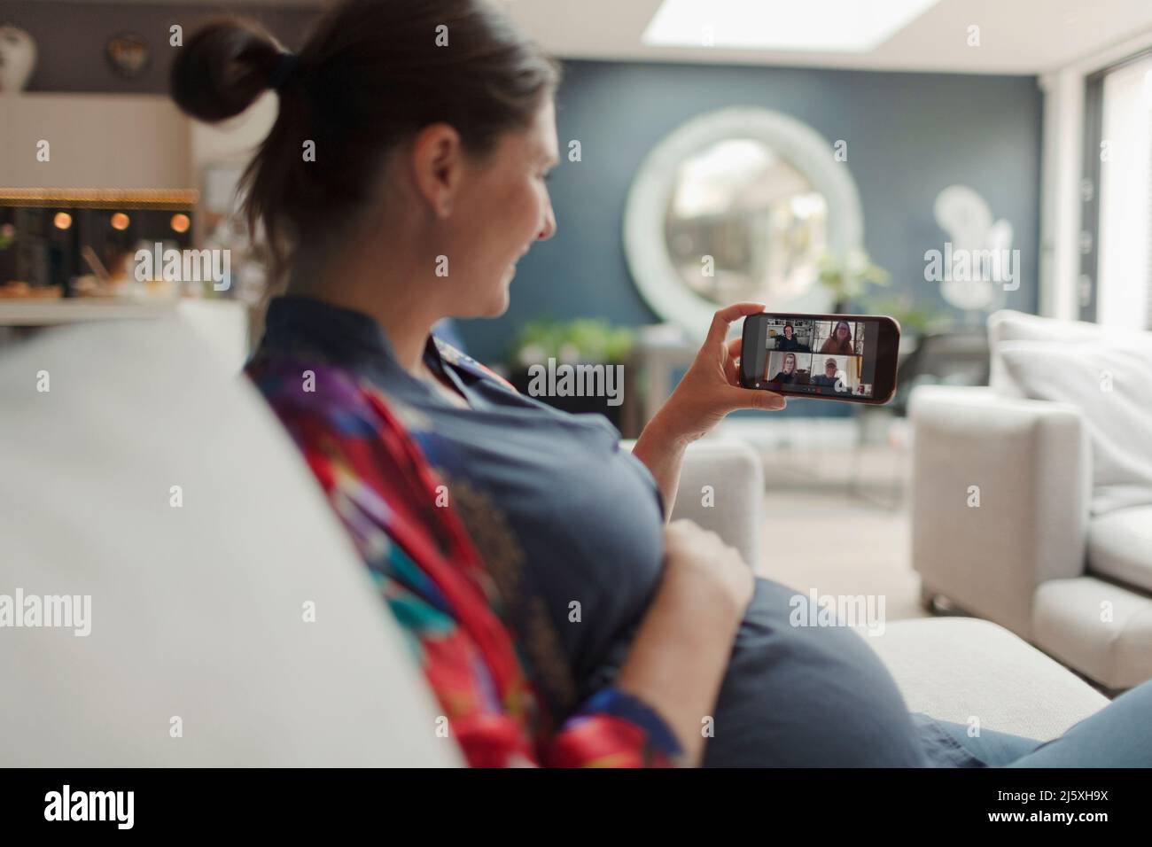 Femme enceinte discutant vidéo avec des amis sur l'écran du smartphone Banque D'Images